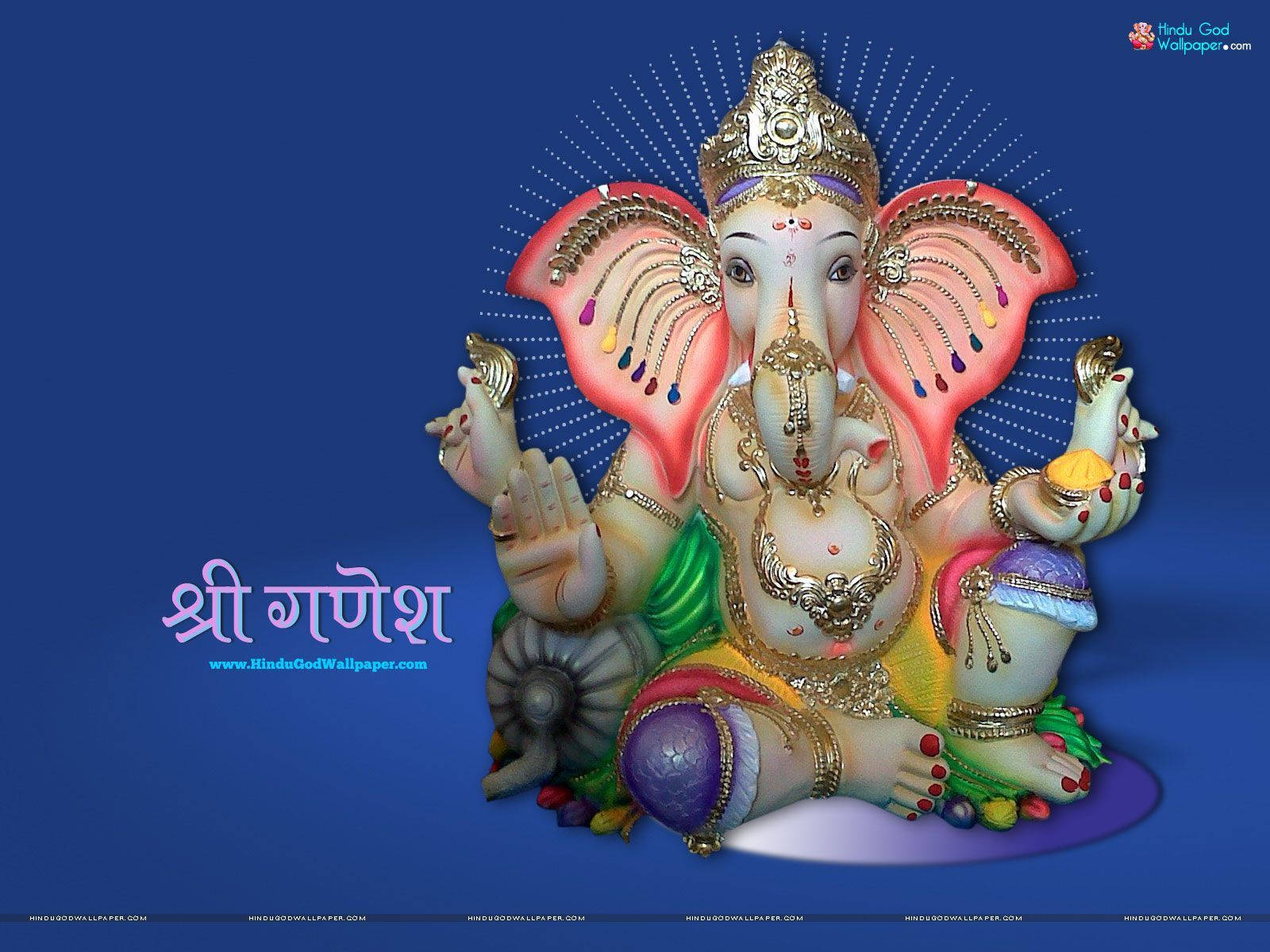 Ganesh 桌布 壁紙 — 一尊色彩繽紛、裝飾華麗的象頭神像，有粉紅色耳朵、金色珠寶和深邃藍色背景上的光環。