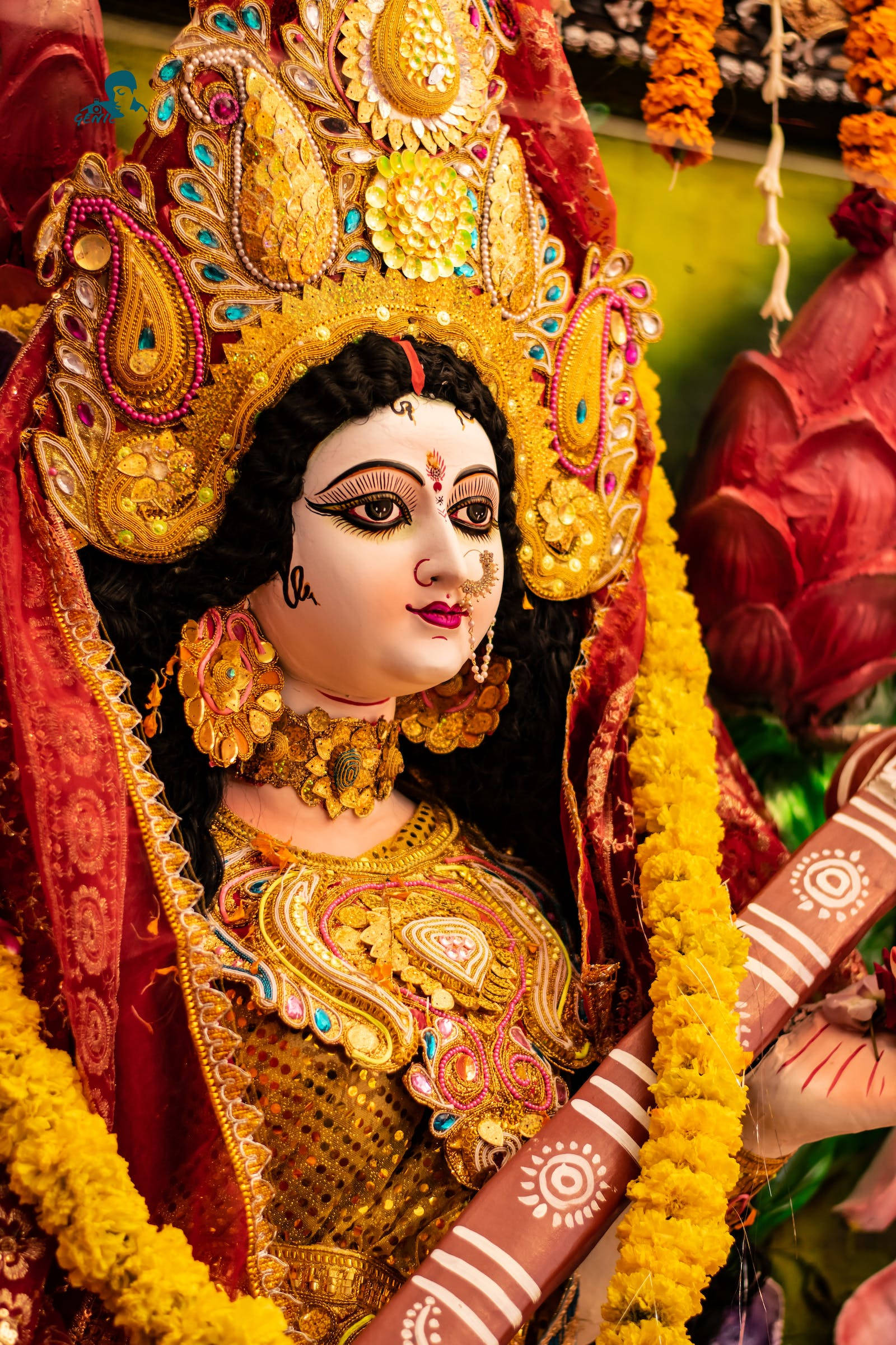 maa durga 桌布 壁紙 — 一尊裝飾華麗的印度教女神雕像，飾有金色珠寶、紅色布料和黃色萬壽菊花環，細節鮮明。