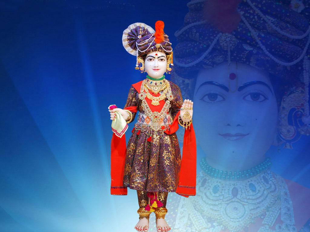 Swaminarayan 桌布 壁紙 — 一尊裝飾華麗的神像，身著華麗的紅色和金色服飾，站在藍色背景前，背景上投射出神聖的面容。