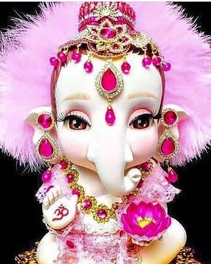 Baby Ganesh 桌布 壁紙 — 一尊裝飾華麗的象神雕像，帶有粉紅色羽毛、黃金首飾和紅寶石，背景為黑色。
