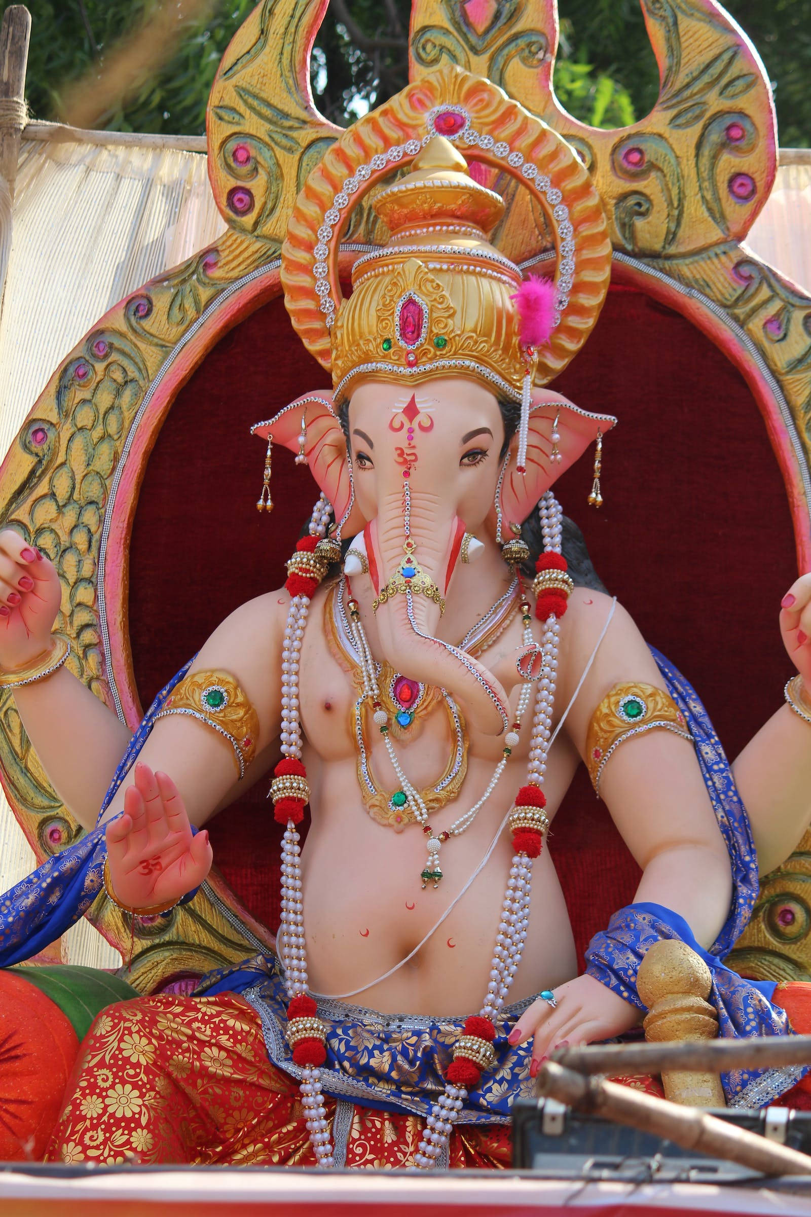 Ganesh 桌布 壁紙 — 一尊裝飾華麗的象頭神像，飾有珠寶和色彩繽紛的布料，威嚴地坐在華麗的寶座上。