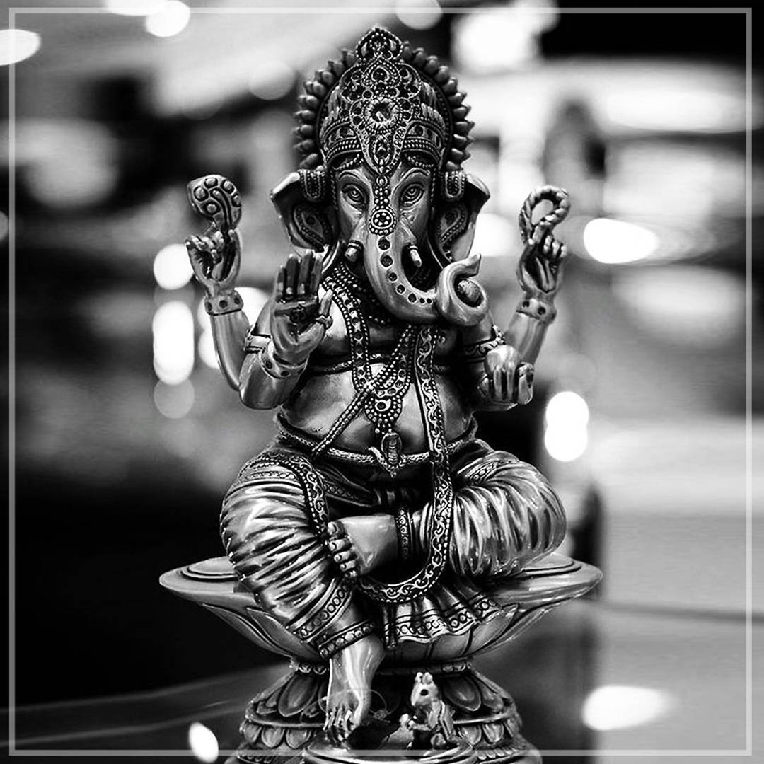 Ganesh 桌布 壁紙 — 一尊詳細的黑白象神甘尼許雕像，安詳地坐在蓮花底座上，帶有精緻雕刻和象徵性手勢。