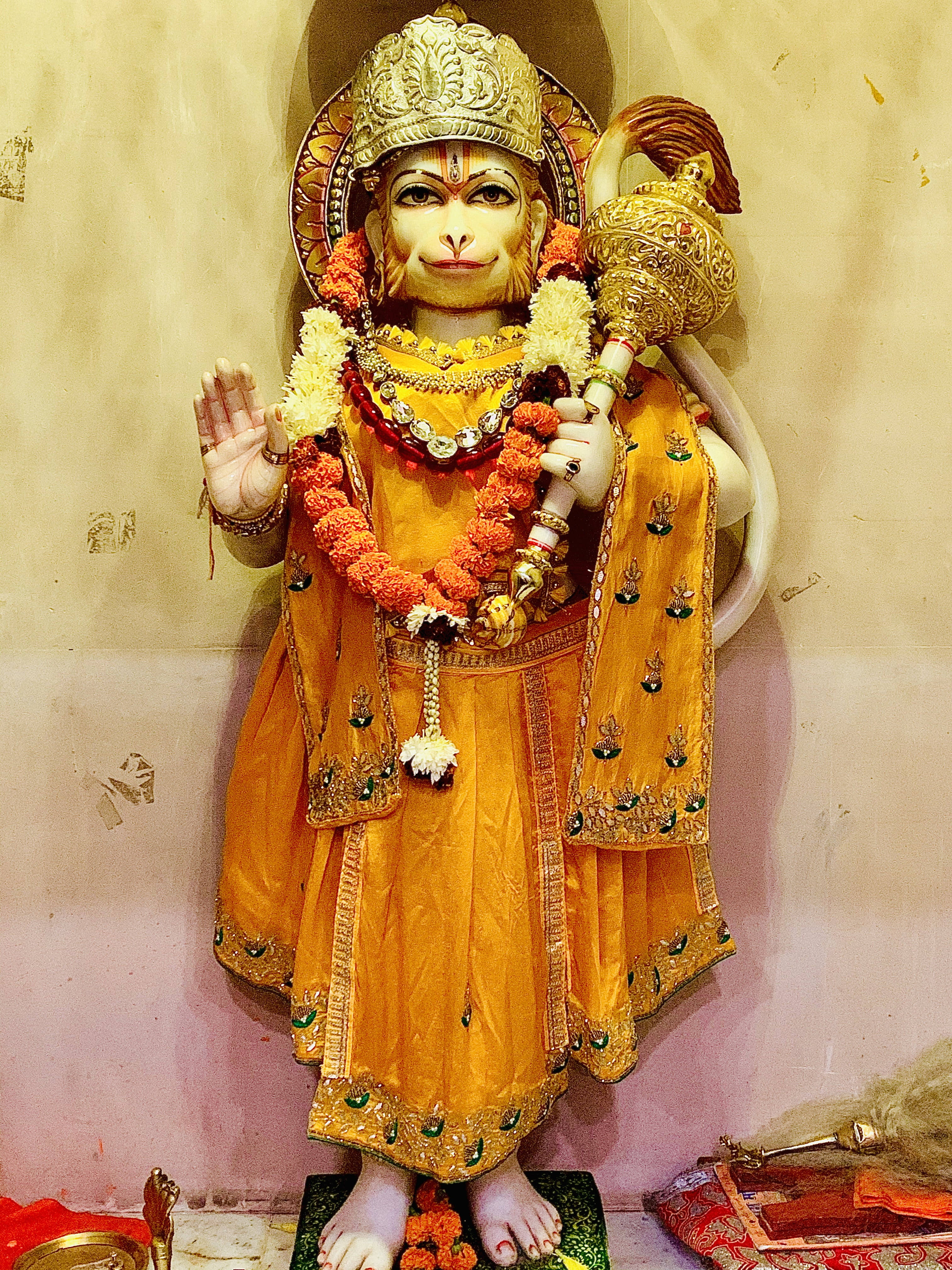 lord hanuman 桌布 壁紙 — 一尊金色的哈努曼雕像，飾有萬壽菊花環和珠寶，矗立在寺廟環境中。