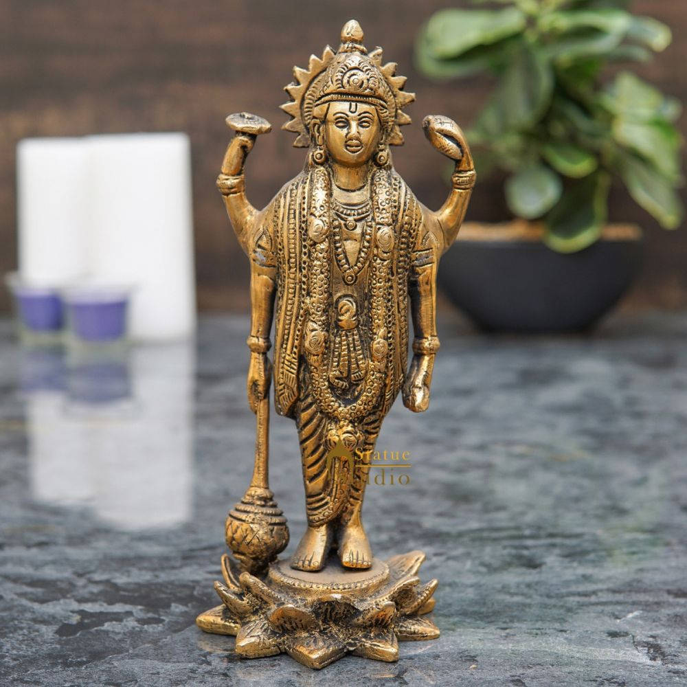 Statue Aesthetic 桌布 壁紙 — 一尊金色的四臂印度教神像，飾有精緻珠寶和太陽光環皇冠，立於深色大理石表面的蓮花底座上。