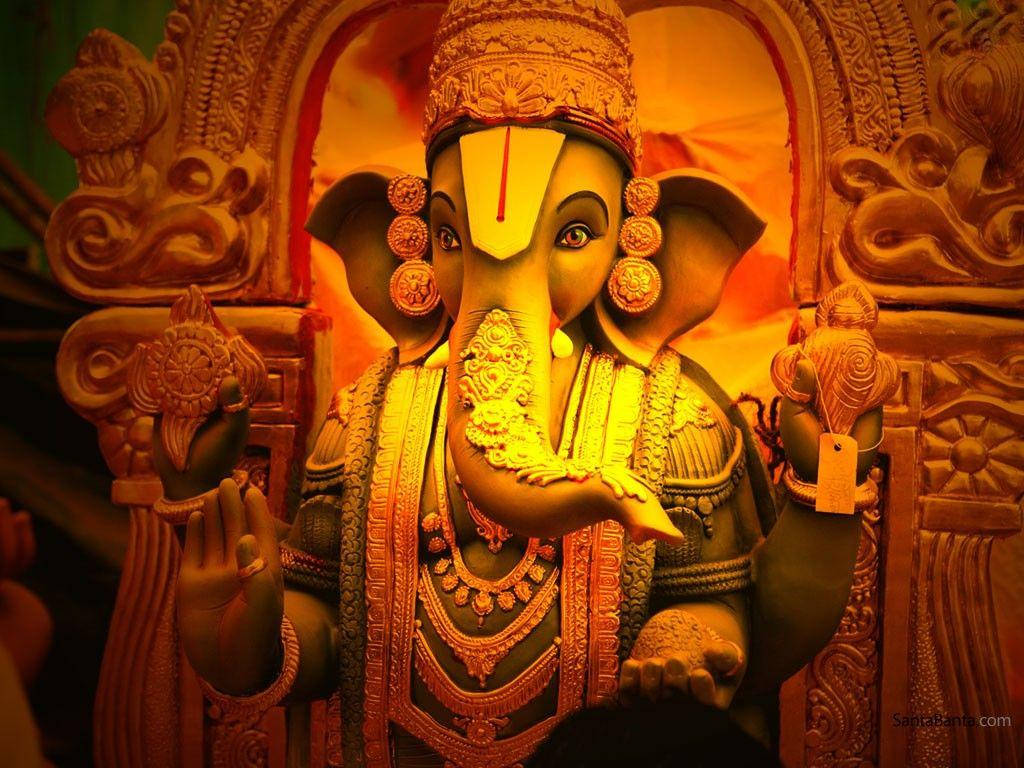ganpati HD 桌布 壁紙 — 一尊金色華麗的象頭神伽內什雕像，擁有象頭和精緻珠寶，在戲劇性燈光下溫暖發光。