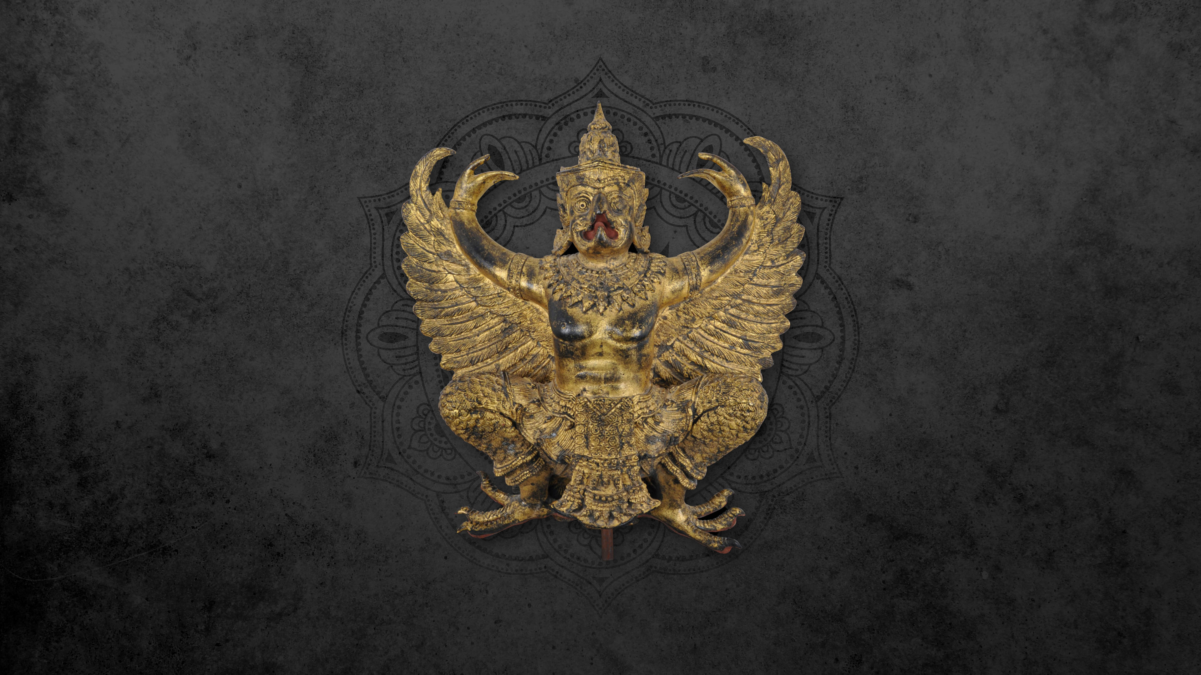 迦樓羅 桌布 壁紙 — 一尊金色華麗的迦樓羅雕像，翅膀展開，細節精緻，矗立在帶有微妙曼陀羅圖案的深色紋理背景前。