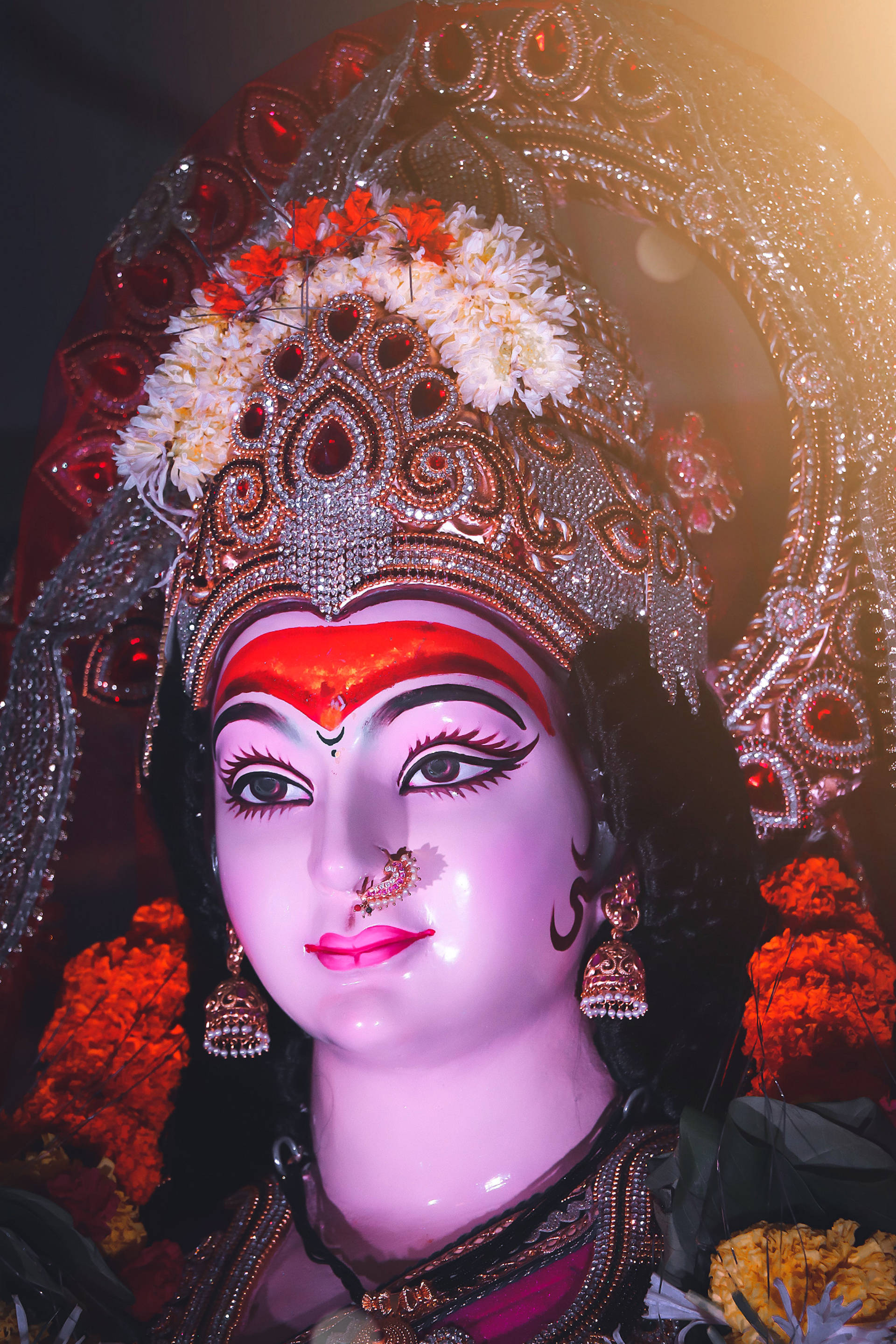 Navratri 桌布 壁紙 — 一尊閃耀的印度教女神雕像，飾有精緻珠寶和花環，沐浴在溫暖的光芒中。