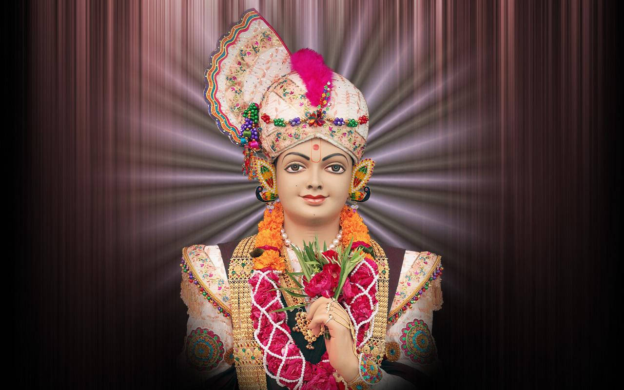 Swaminarayan 桌布 壁紙 — 一尊閃耀的神像，飾以色彩繽紛的珠寶和花環，背景是發光的光芒。