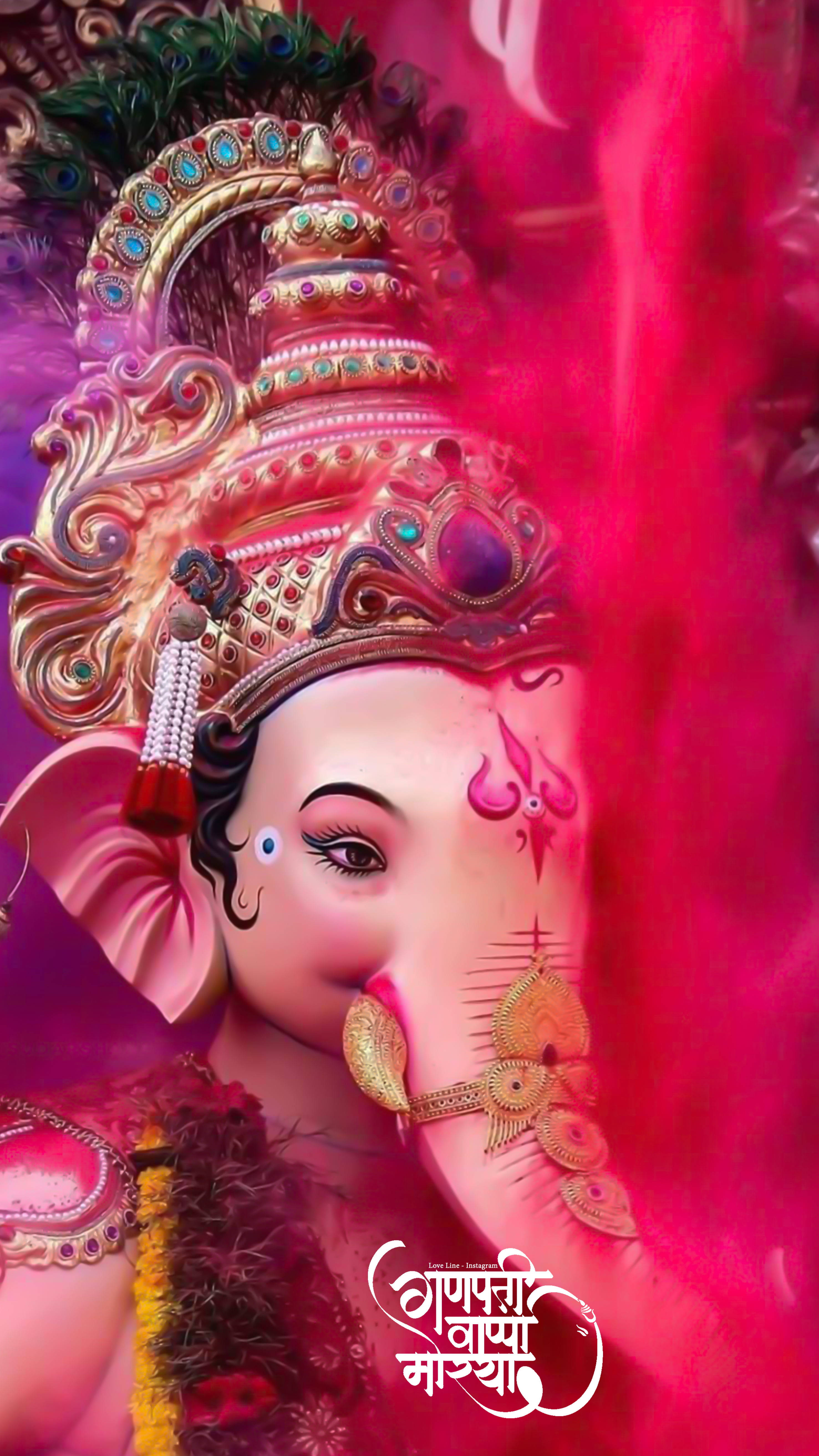 hindu iPhone 桌布 壁紙 — 一尊閃耀的粉紅色象神雕像，飾有黃金珠寶和孔雀羽毛，背景為鮮豔的洋紅色。