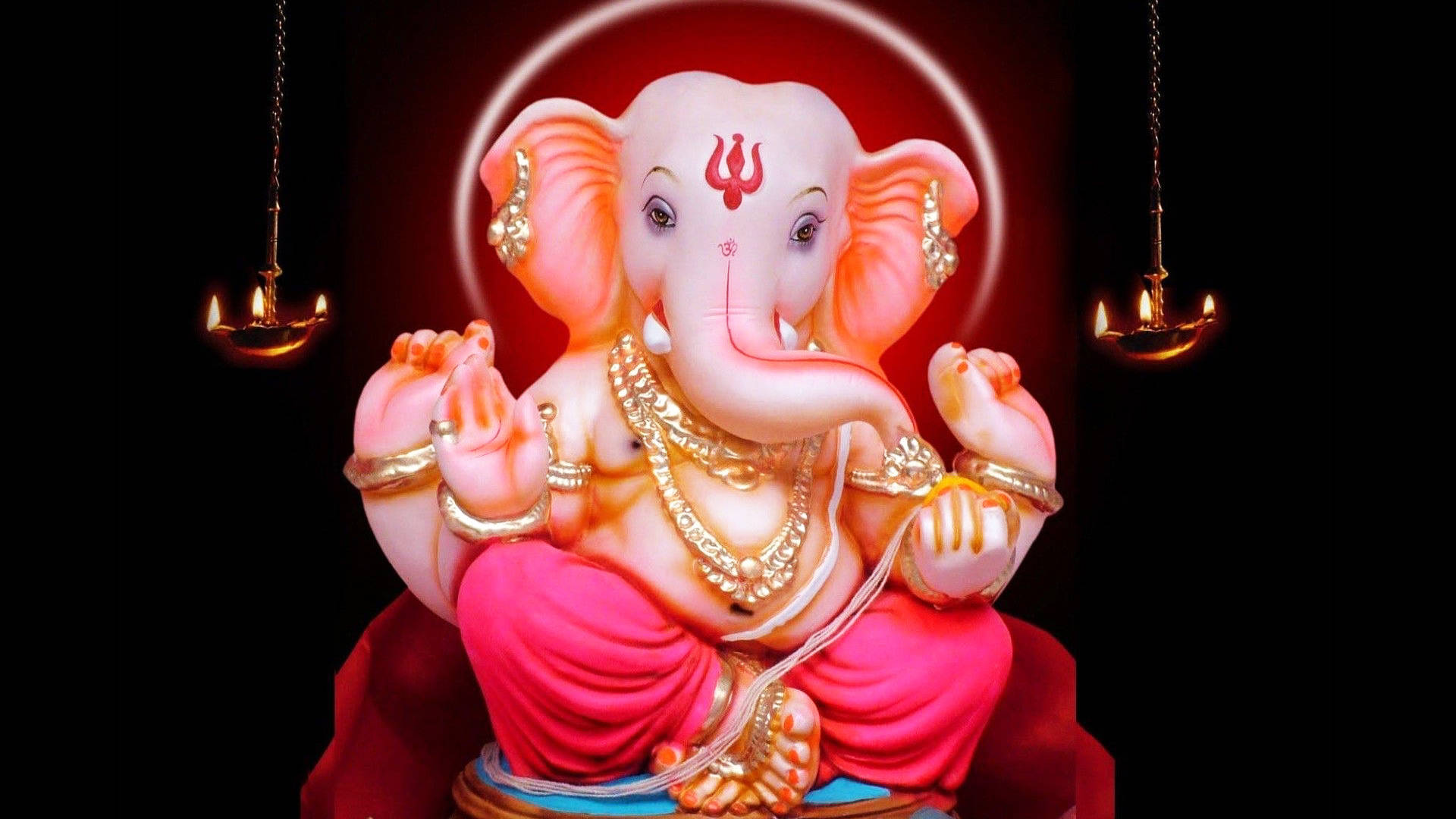 cute ganesha 桌布 壁紙 — 一尊閃耀的粉紅色象頭神雕像，飾有黃金珠寶，在懸掛油燈的發光光環下寧靜地坐著。