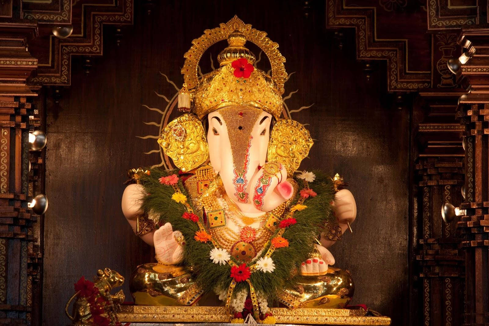 ganpati HD 桌布 壁紙 — 一尊閃耀的金色象頭神像，飾以色彩繽紛的花朵和精緻珠寶，莊嚴地安坐於華麗的寺廟神龕中。