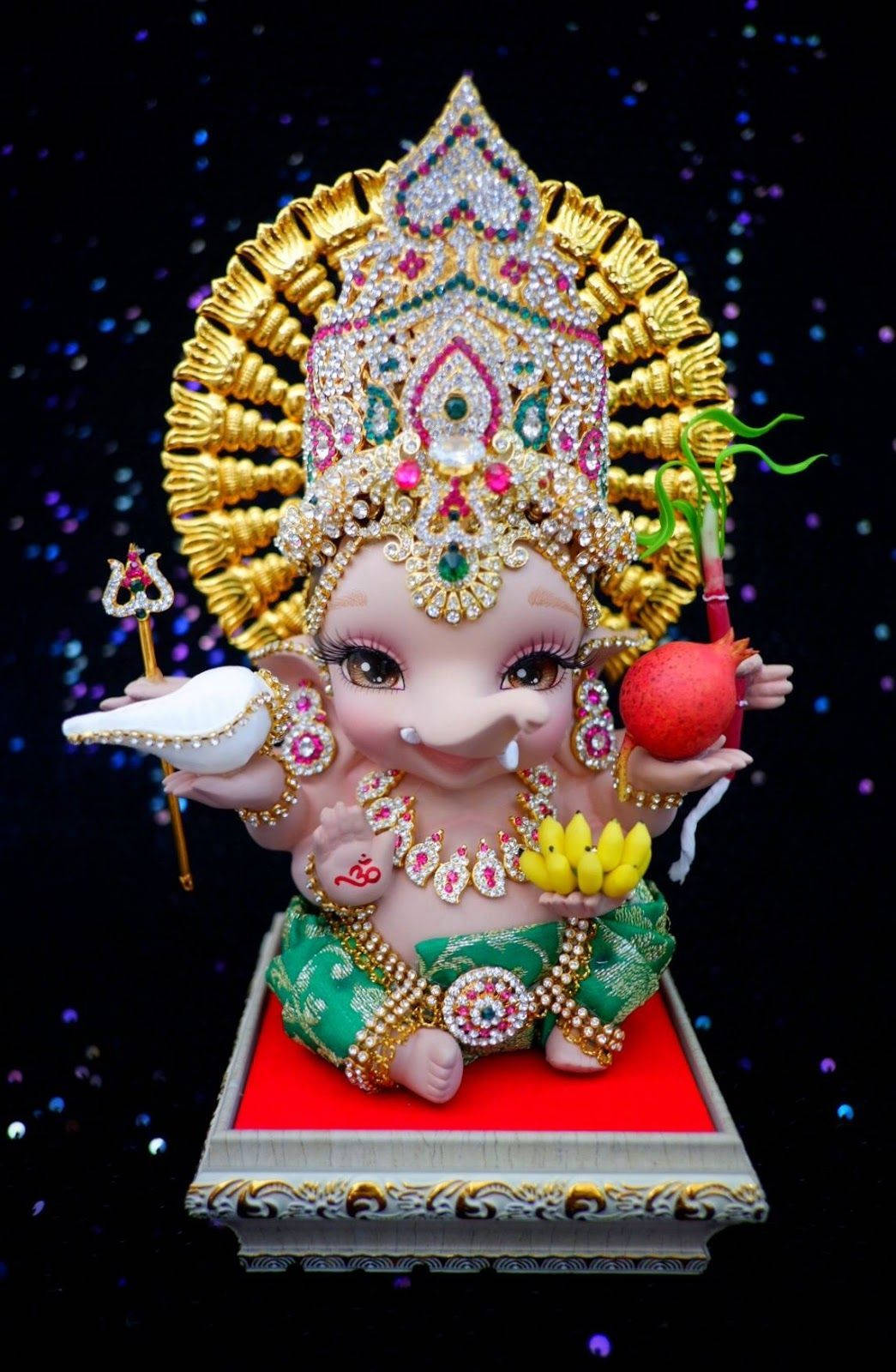 cute ganesha 桌布 壁紙 — 一尊閃閃發光的嬰兒象神雕像，飾有寶石和黃金，坐在紅色基座上，背景是閃爍的星空。
