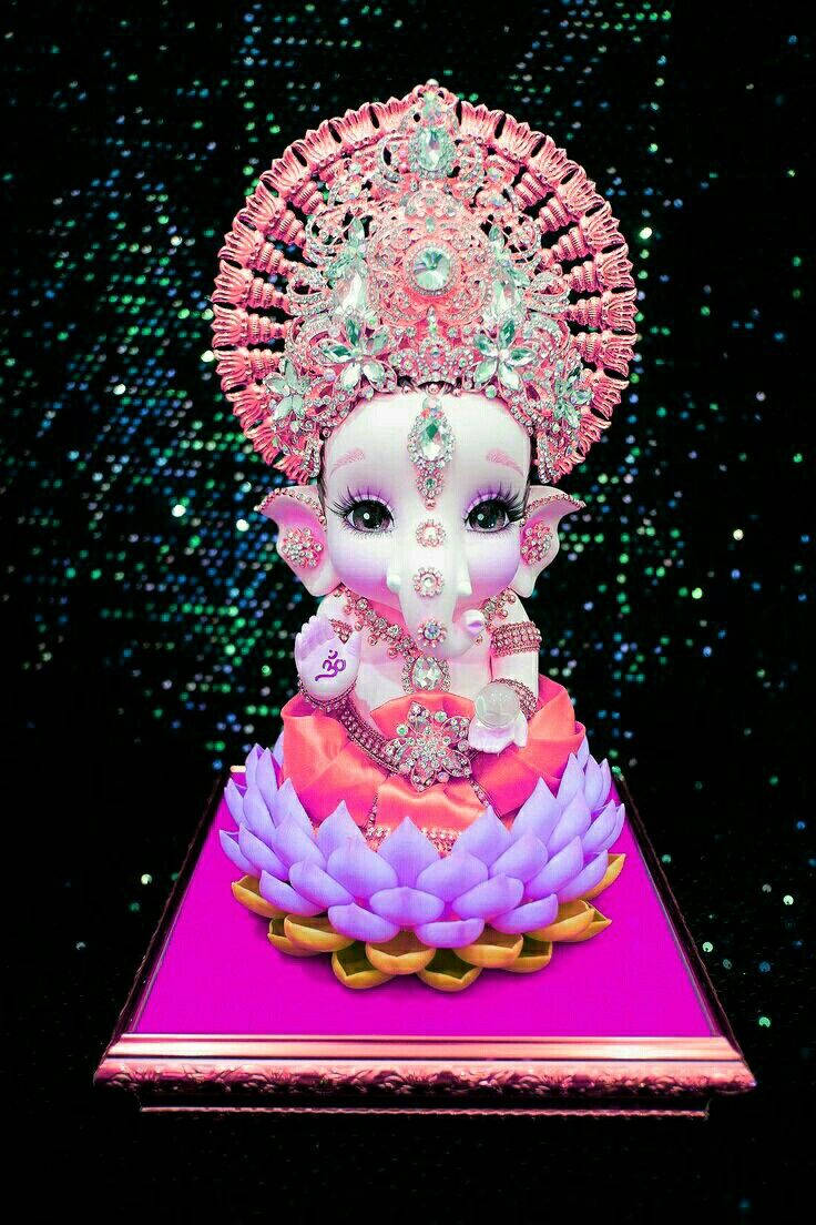 laxmi ganesh saraswati 桌布 壁紙 — 一尊閃閃發光的粉紅色和紫色象神雕像，飾有珠寶，坐在洋紅色底座上的蓮花上，背景是閃爍的深色。