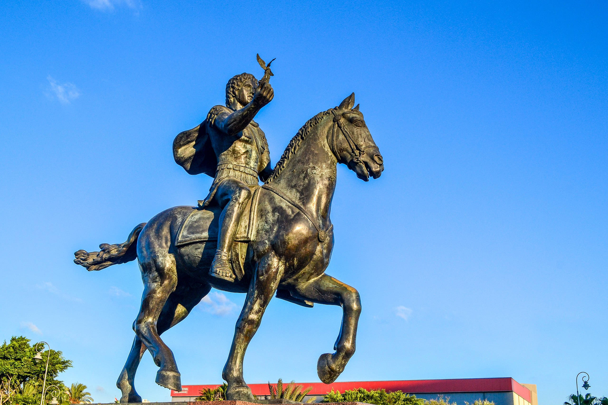 Alexandria 桌布 壁紙 — 一尊雄偉的羅馬士兵騎馬青銅雕像，手持鳥兒，背景是清澈的藍天。
