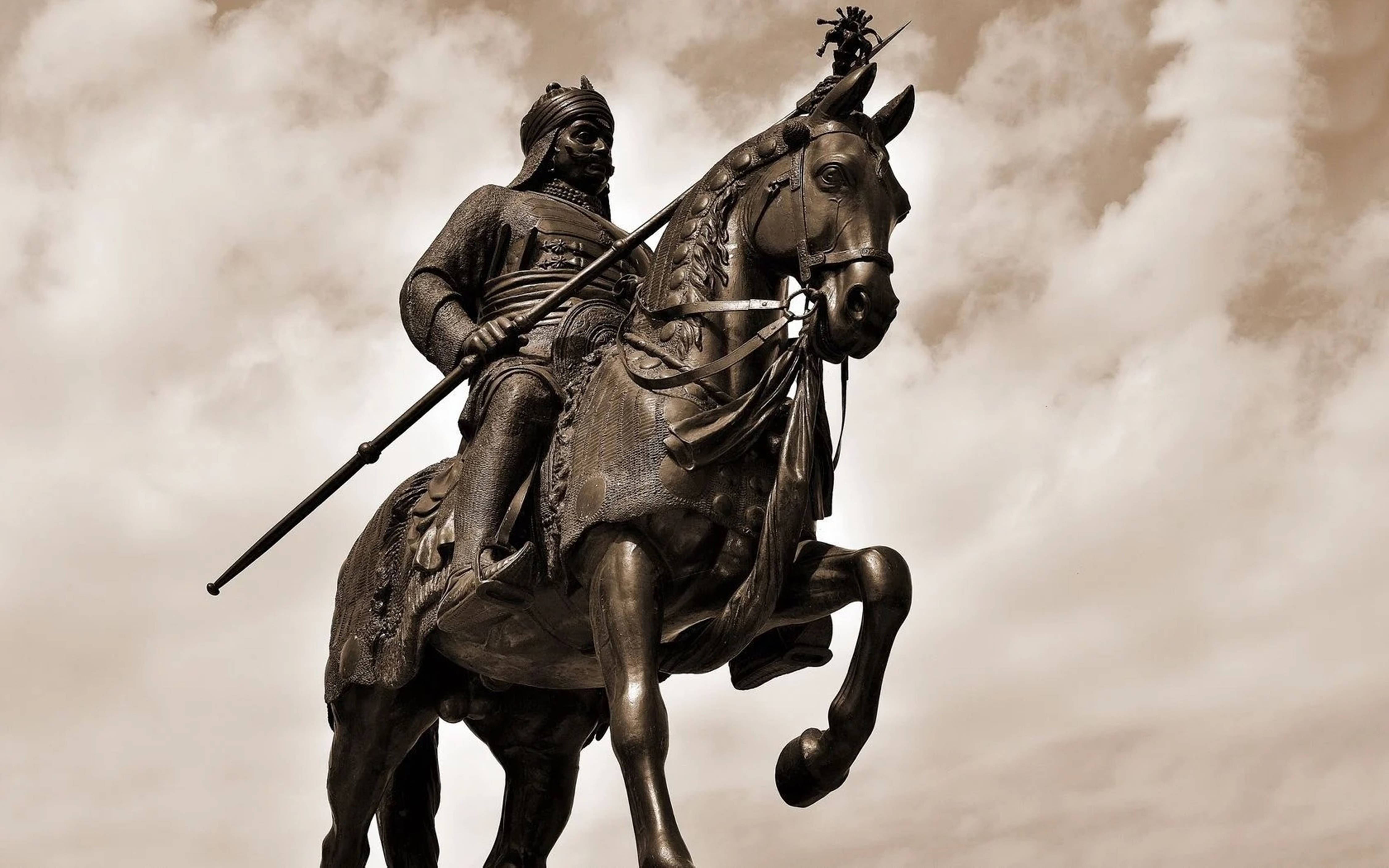 Indian 桌布 壁紙 — 一尊雄偉的青銅騎馬戰士雕像，戰士騎在後腿站立的馬上，背景是陰天。