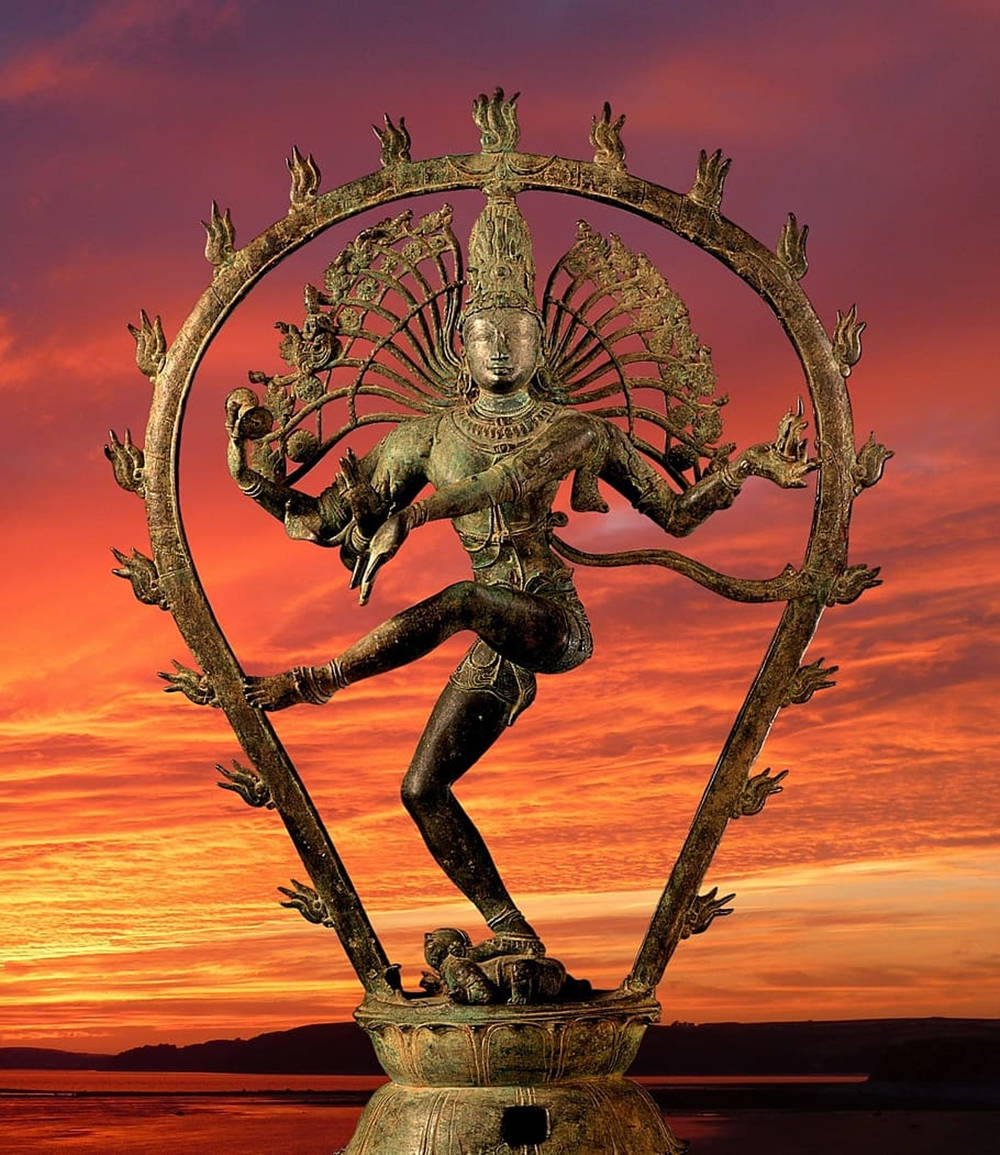 lord shiva mobile 桌布 壁紙 — 一尊青銅濕婆像在宇宙之火中跳舞，背景是充滿活力的日落天空。