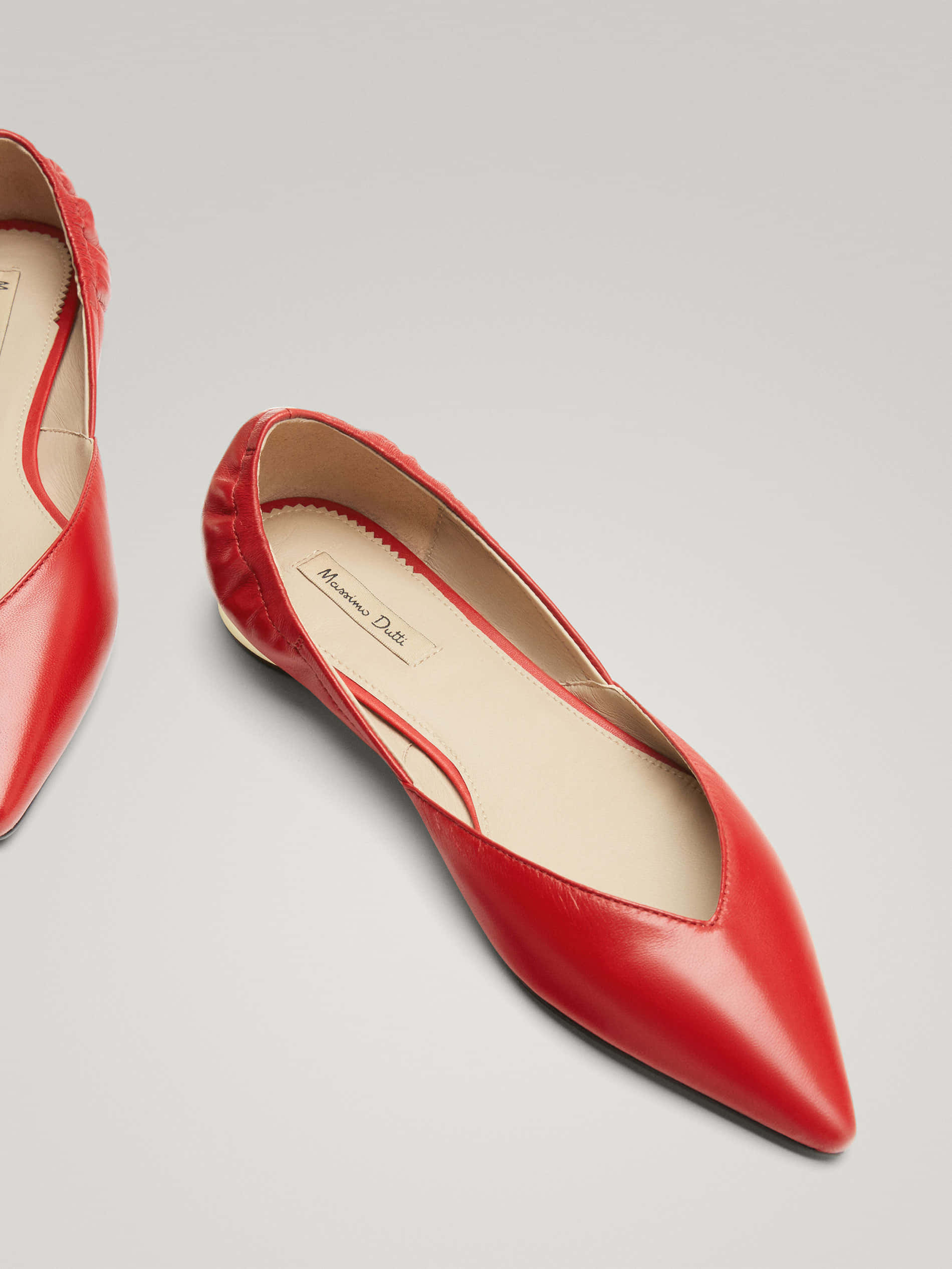 Red Shoes 桌布 壁紙 — 一對亮面紅色尖頭平底鞋，帶有褶皺細節和奶油色鞋墊，置於中性灰色背景上。