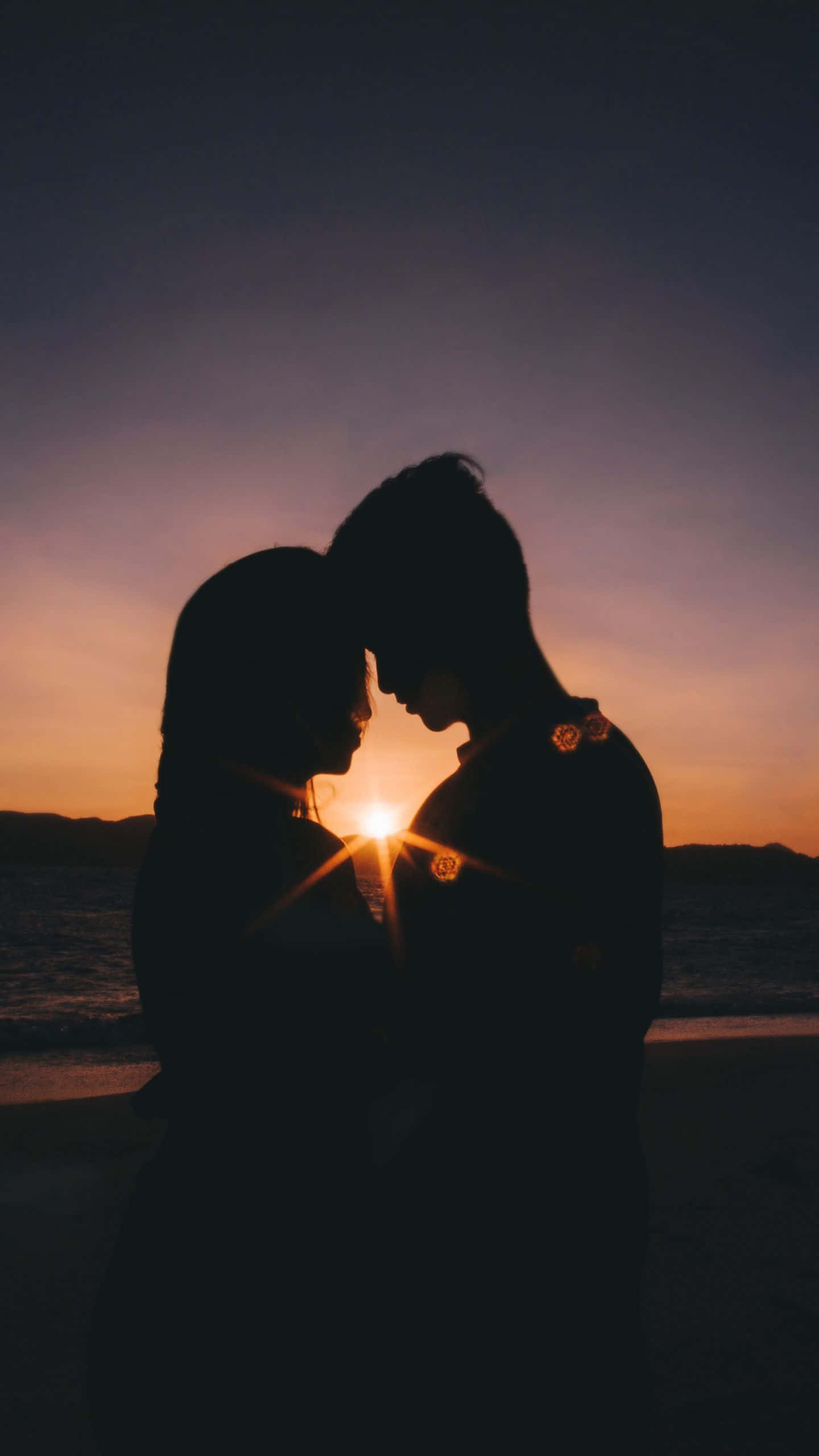 lovely 桌布 壁紙 — 一對剪影情侶在寧靜的海灘上，夕陽在他們身後落下，分享親密時刻。