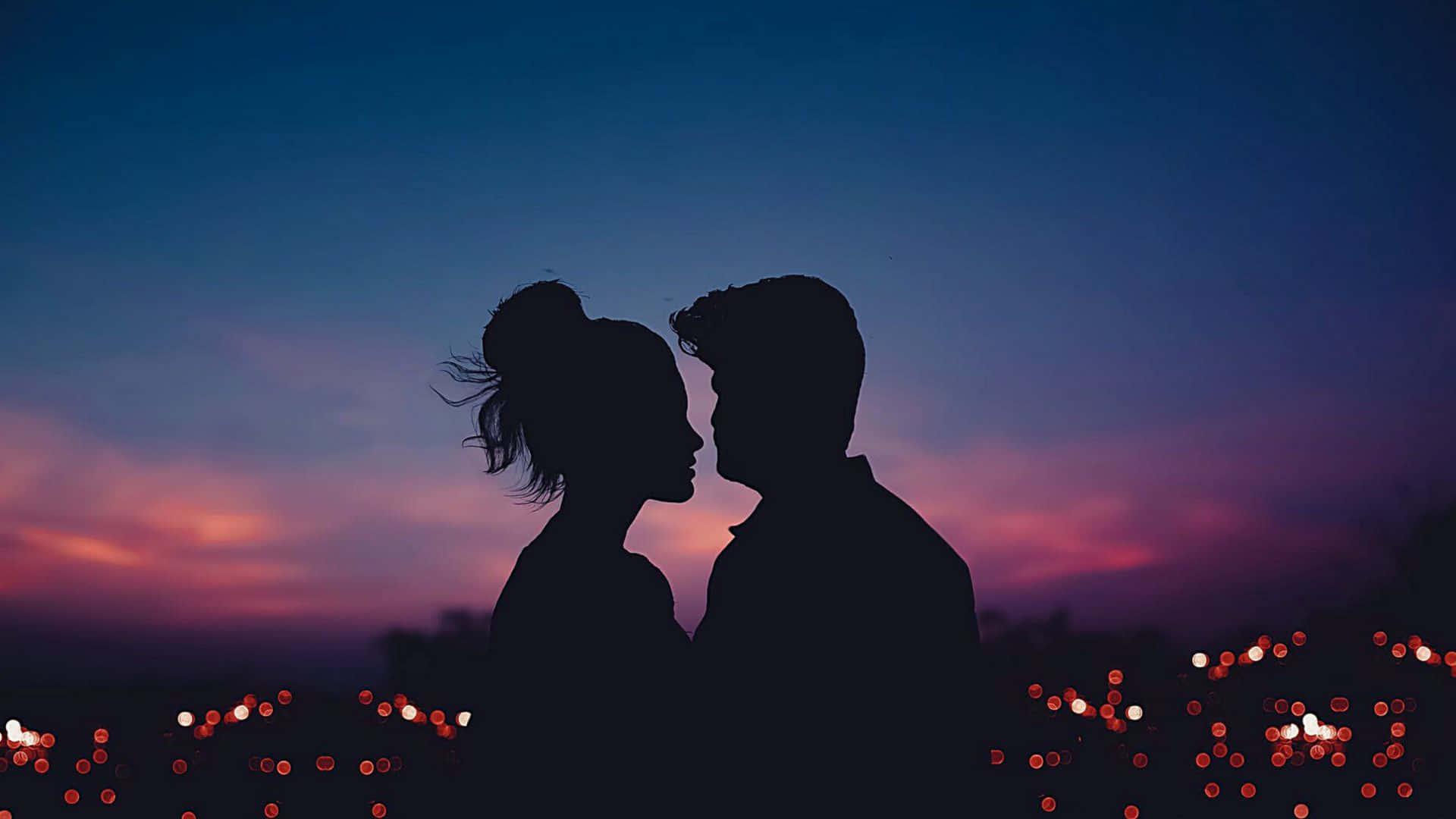Beautiful Love 桌布 壁紙 — 一對剪影情侶在紫色和橙色條紋的暮色天空下，於模糊的城市燈光之上分享親密時刻。