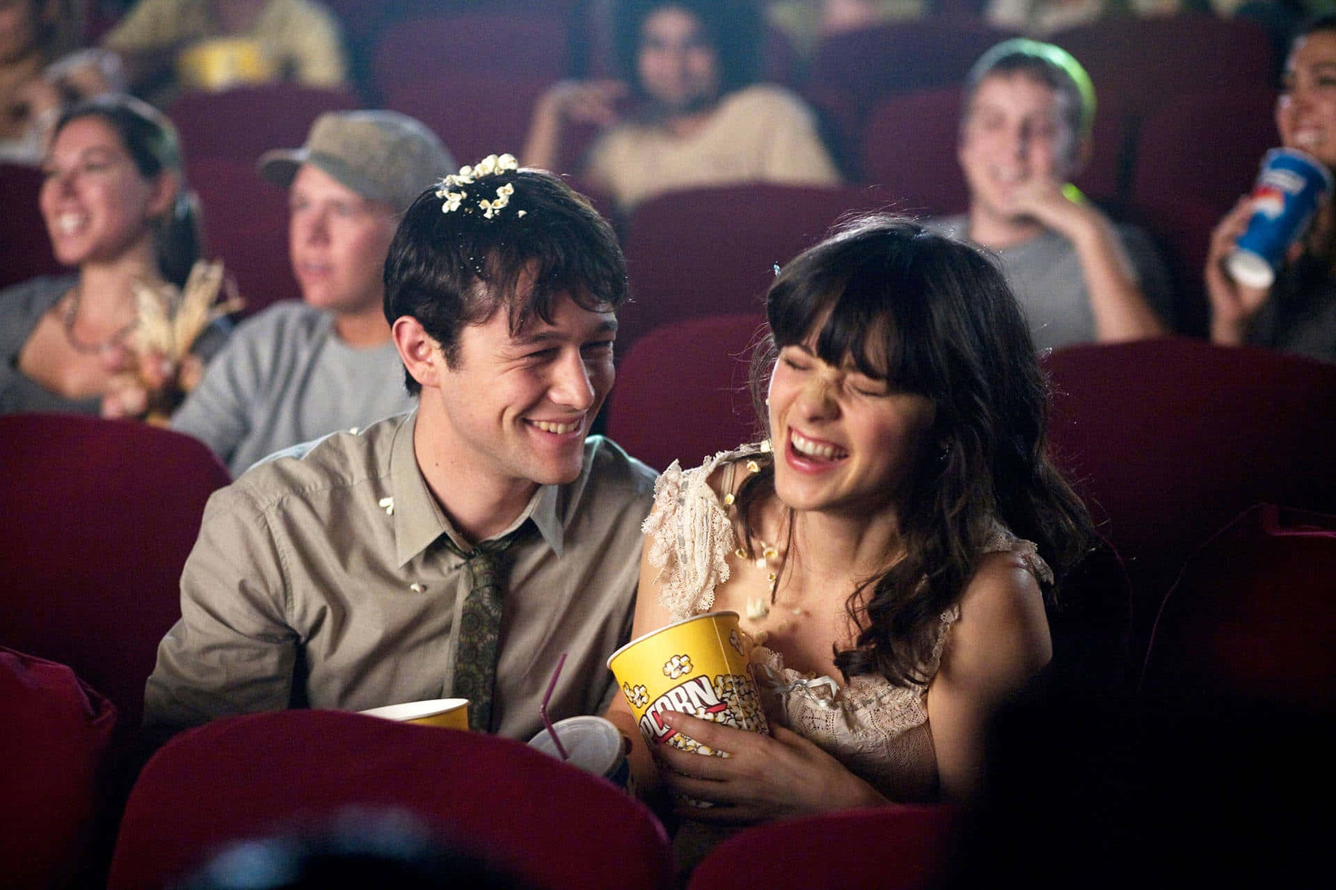 500 Days Of Summer 桌布 壁紙 — 一對大笑的情侶在昏暗的戲院裡與其他觀眾分享爆米花。