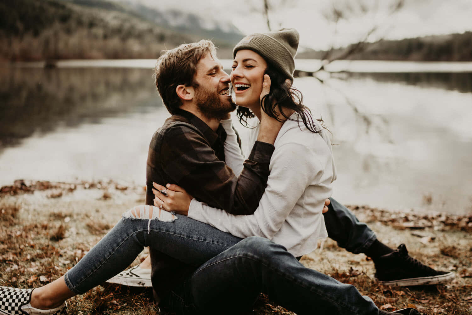 Couple Photography 桌布 壁紙 — 一對大笑的情侶在霧氣瀰漫的湖邊擁抱，四周是光禿的樹木和落葉。