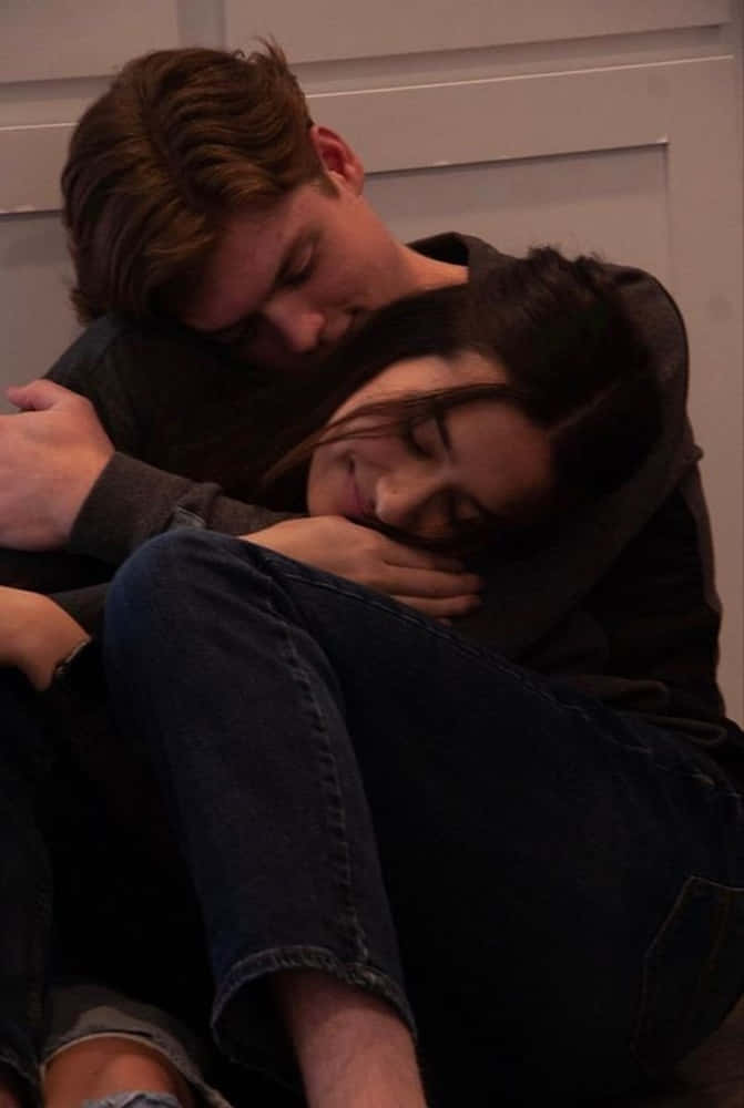 Girlfriend And Boyfriend 桌布 壁紙 — 一對年輕情侶在地板上親密擁抱，男人輕輕地抱著女人，女人將頭靠在他的肩膀上，房間燈光昏暗。