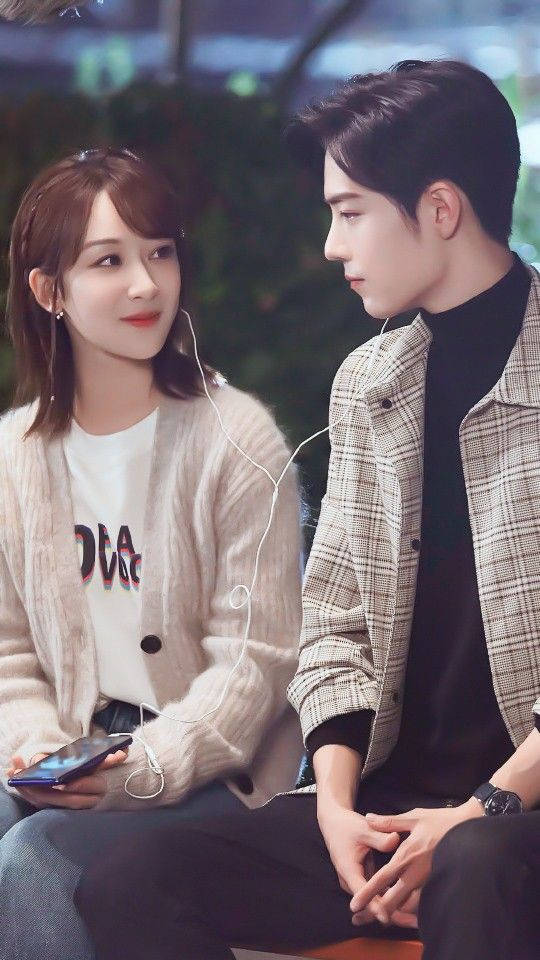 Couples 桌布 壁紙 — 一對年輕情侶在柔和燈光的城市環境中緊靠在一起分享耳機。