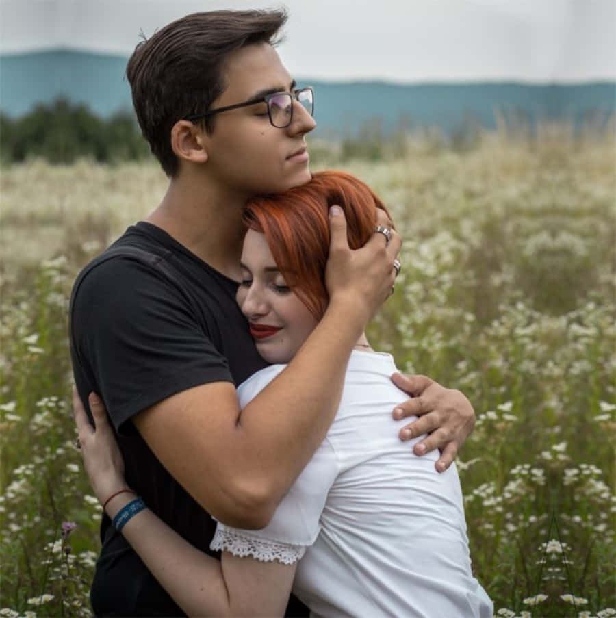 Hug 桌布 壁紙 — 一對年輕情侶在陰天下的白色野花田裡溫柔擁抱。