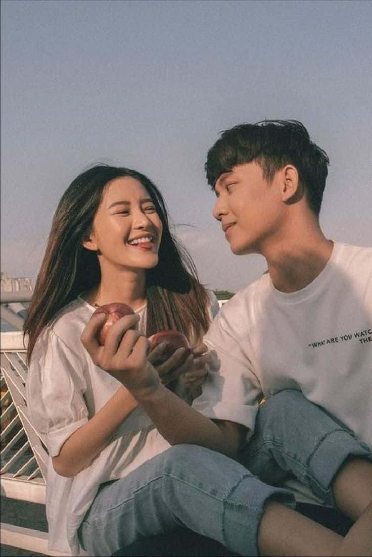 Couples 桌布 壁紙 — 一對年輕情侶在黃金時刻於屋頂上拿著蘋果，溫暖地微笑著。