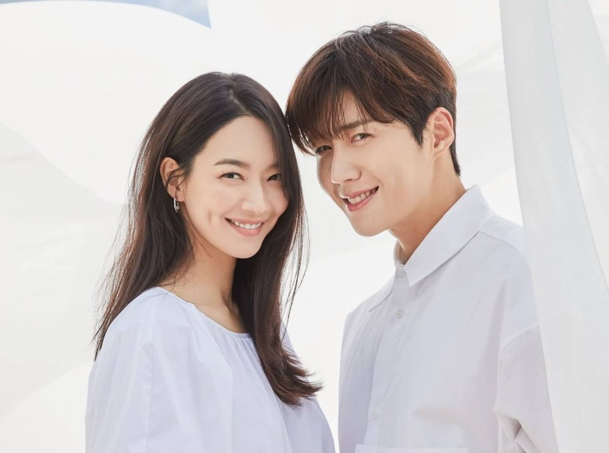 Kim Seon Ho 桌布 壁紙 — 一對微笑的年輕情侶穿著白色襯衫，在柔軟的白色布料下緊密站立，散發溫暖和愛意。