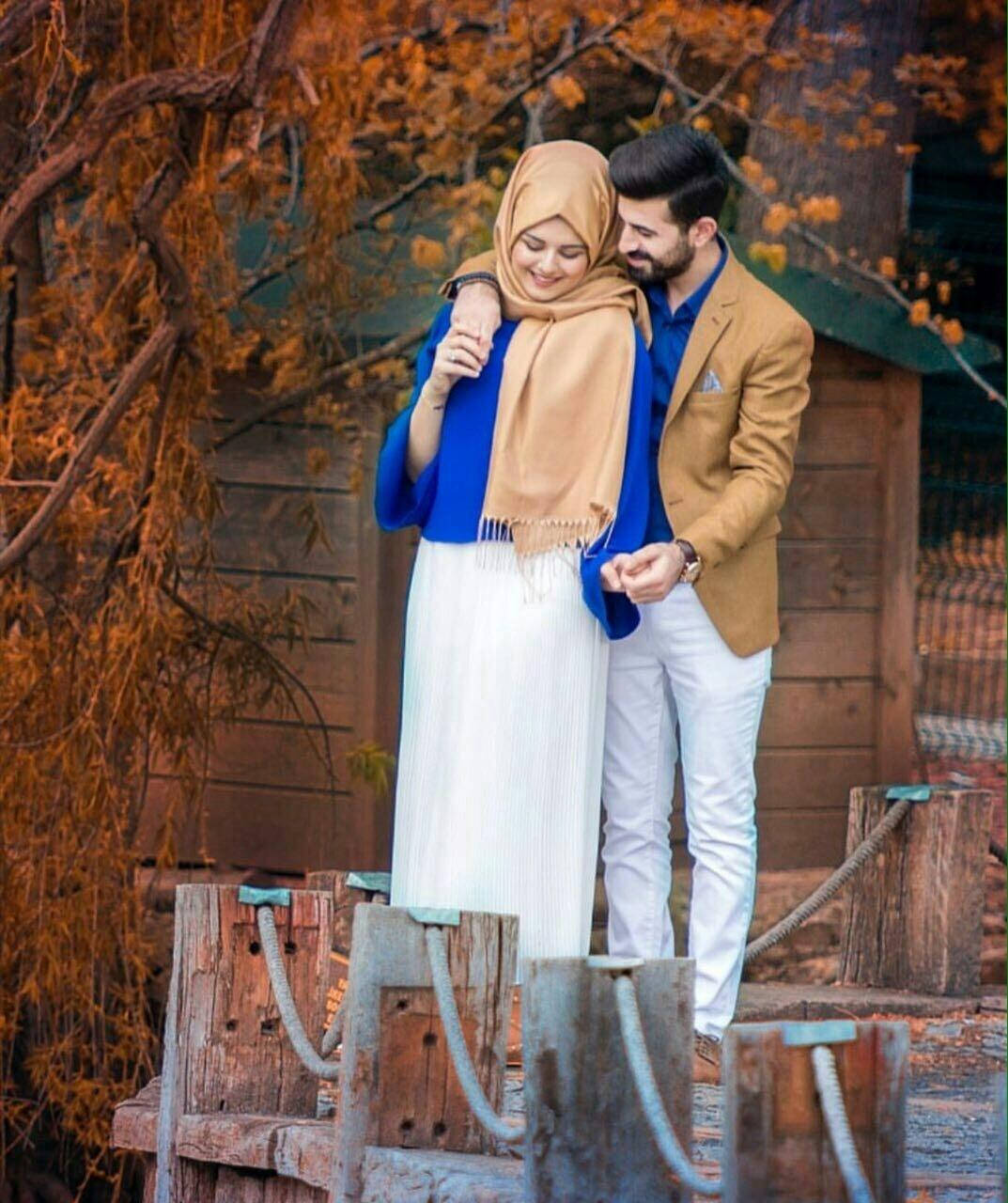 muslim 桌布 壁紙 — 一對微笑的情侶在充滿活力的秋葉和質樸的木柱中溫暖地擁抱。