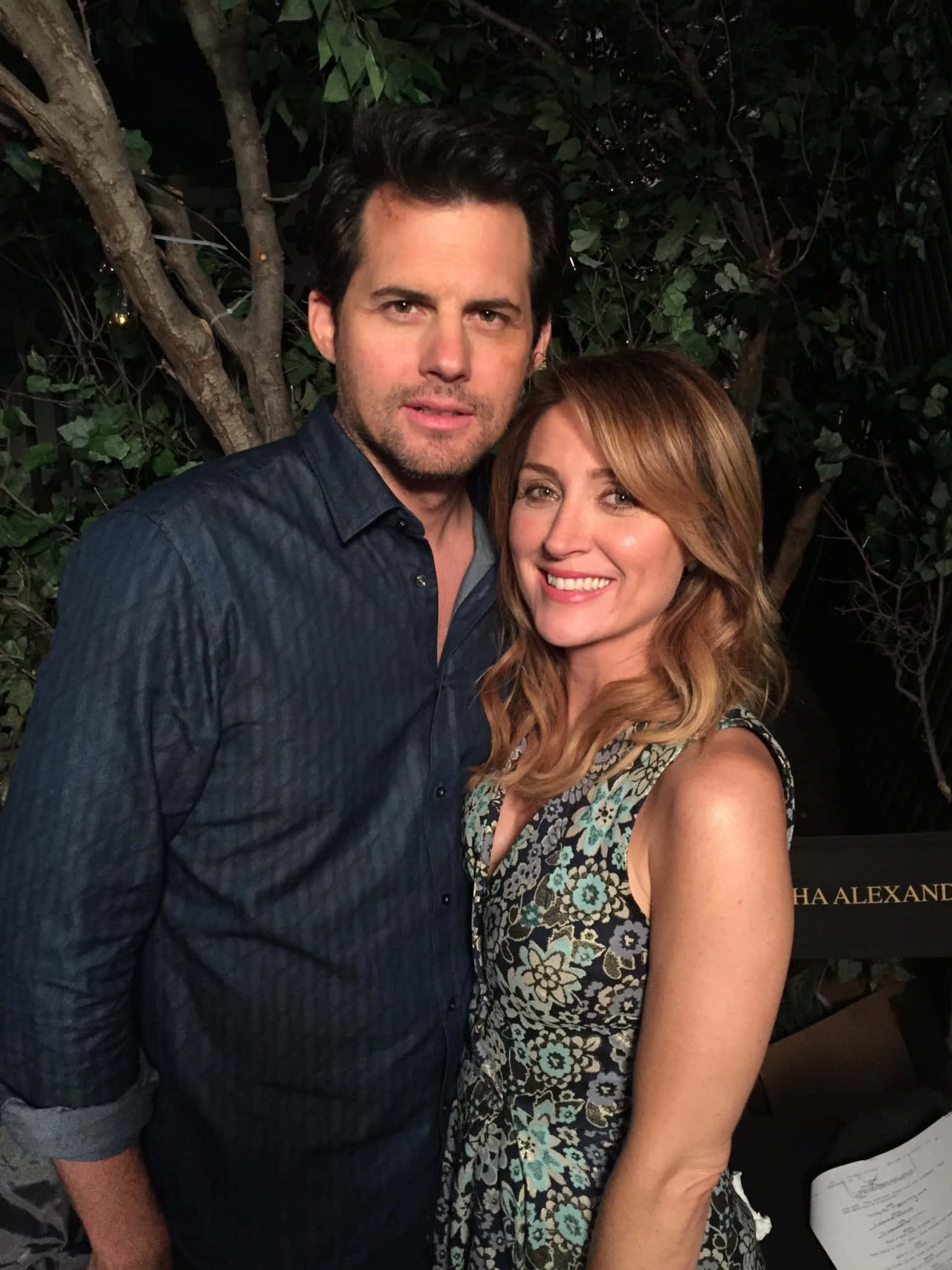 Sasha Alexander 桌布 壁紙 — 一對微笑的情侶在夜晚靠近彼此，身後有樹木，在柔和燈光下擺姿勢。