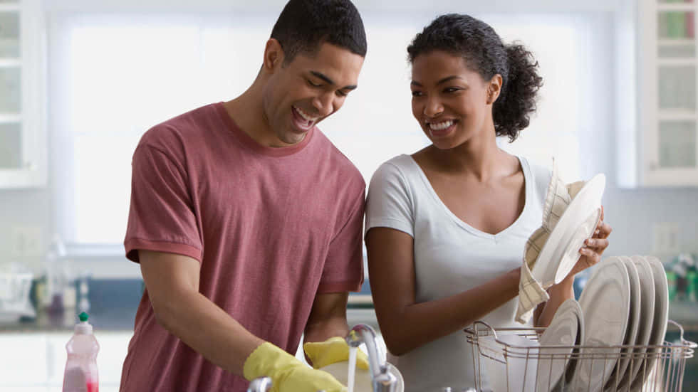 Black Couple 桌布 壁紙 — 一對微笑的情侶在明亮現代化的廚房裡快樂地一起洗碗。