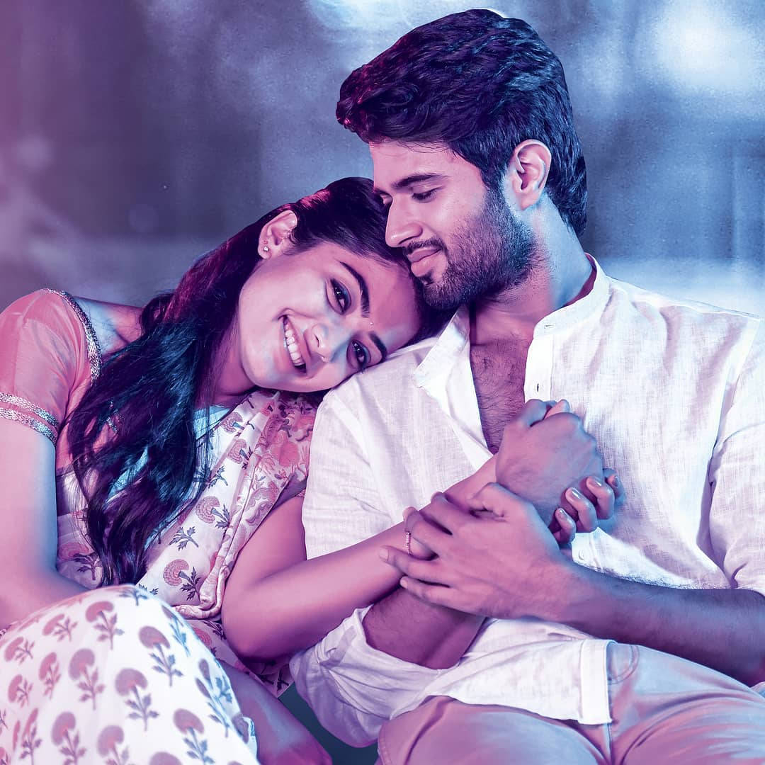 vijay devarakonda 4K 桌布 壁紙 — 一對微笑的情侶在柔和的紫色和藍色燈光下，背景模糊，溫柔地擁抱。
