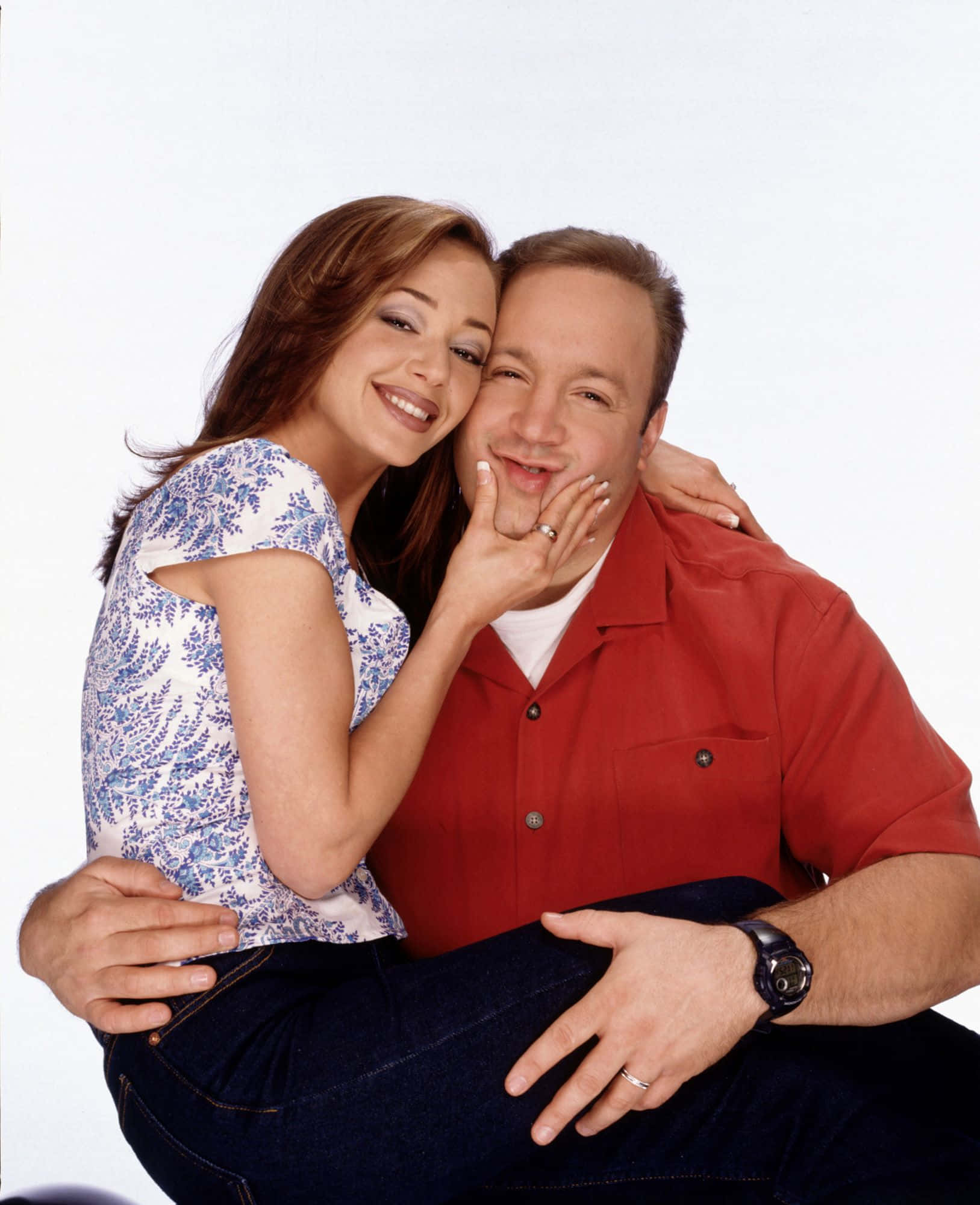 Kevin James 桌布 壁紙 — 一對微笑的情侶在純白背景前溫暖擁抱，女方輕觸男方的臉頰。