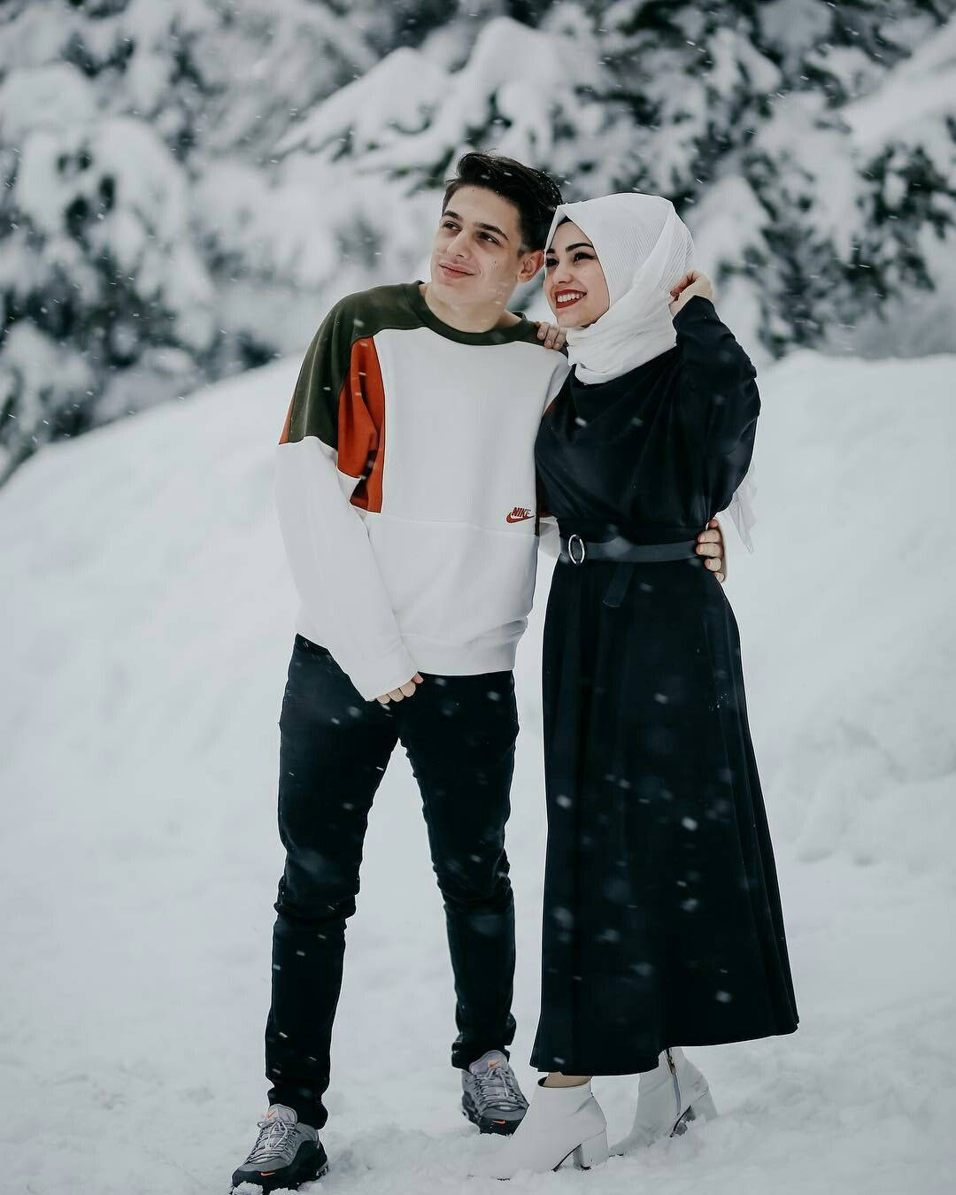 muslim 桌布 壁紙 — 一對微笑的情侶在雪森林中擁抱，雪花在他們周圍飄落。