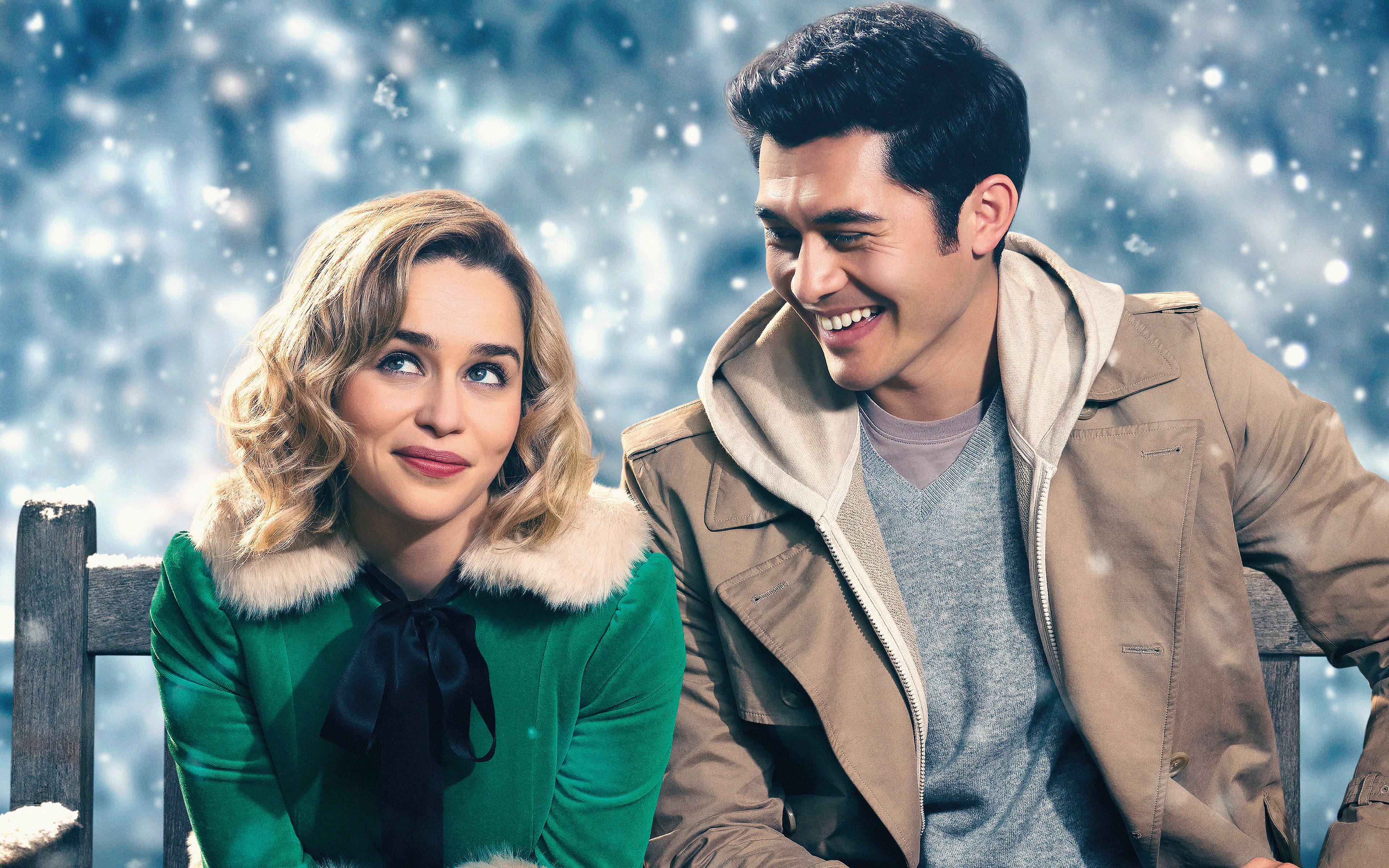 Emilia 桌布 壁紙 — 一對微笑的情侶在飄雪下緊靠坐在雪白的長椅上，背景是冬日藍色。
