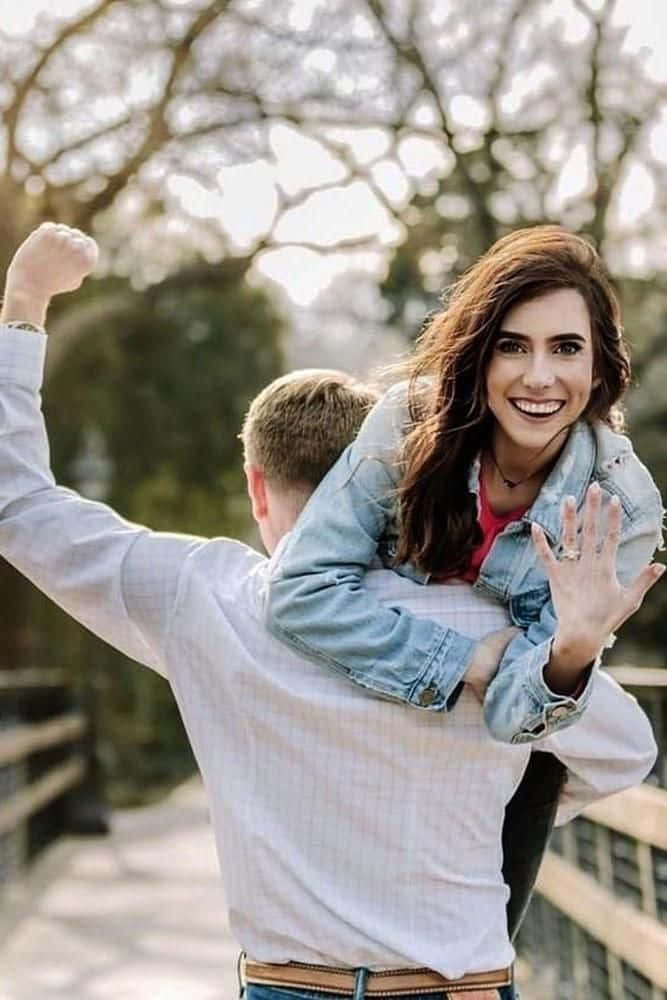 engagement 桌布 壁紙 — 一對快樂的情侶分享一個玩樂時刻，女子燦爛微笑，騎在男子背上，男子則勝利地舉起拳頭。