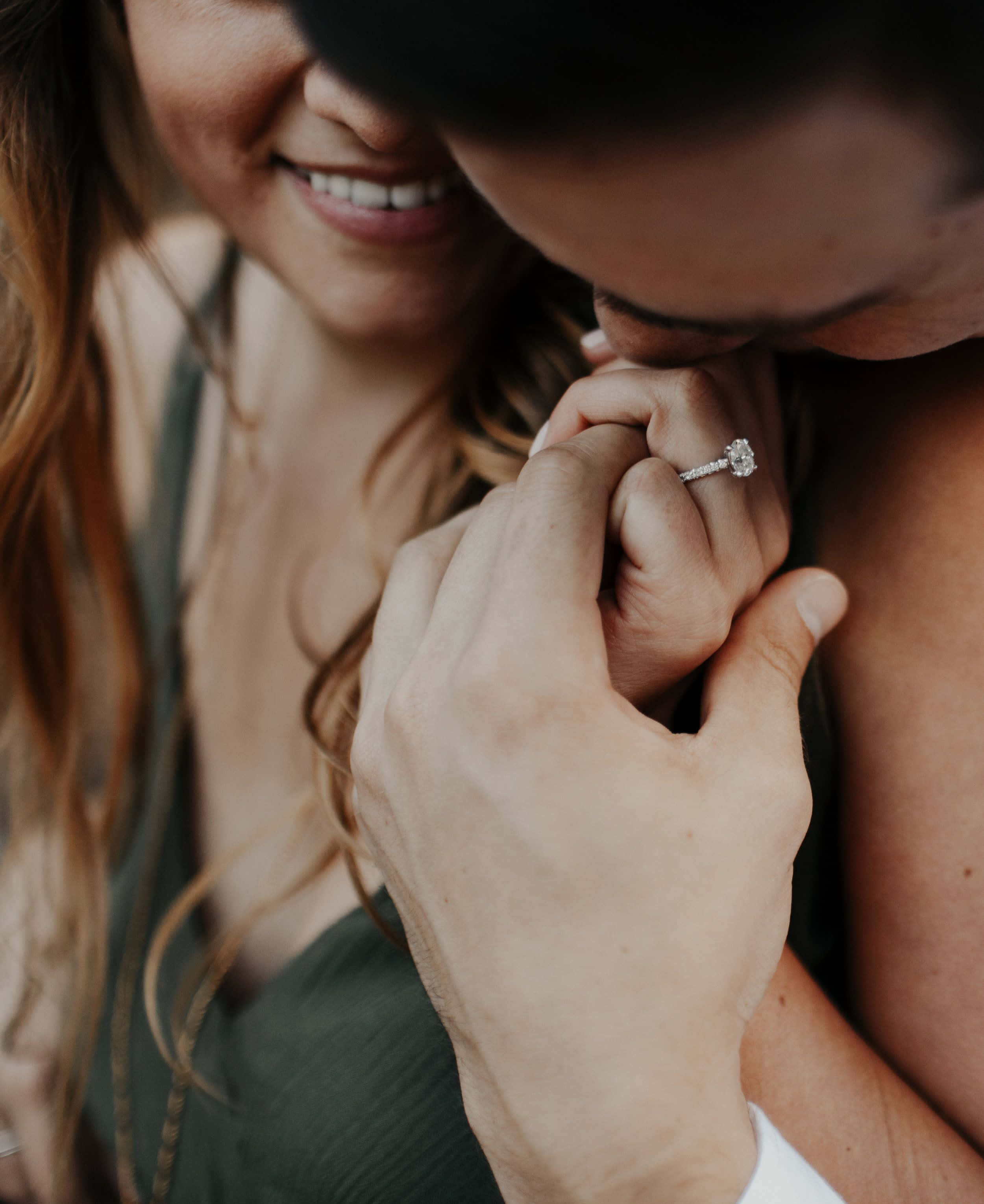 Kissing 桌布 壁紙 — 一對快樂的情侶分享親密時刻，男人親吻女人戴著閃亮鑽石訂婚戒指的手。