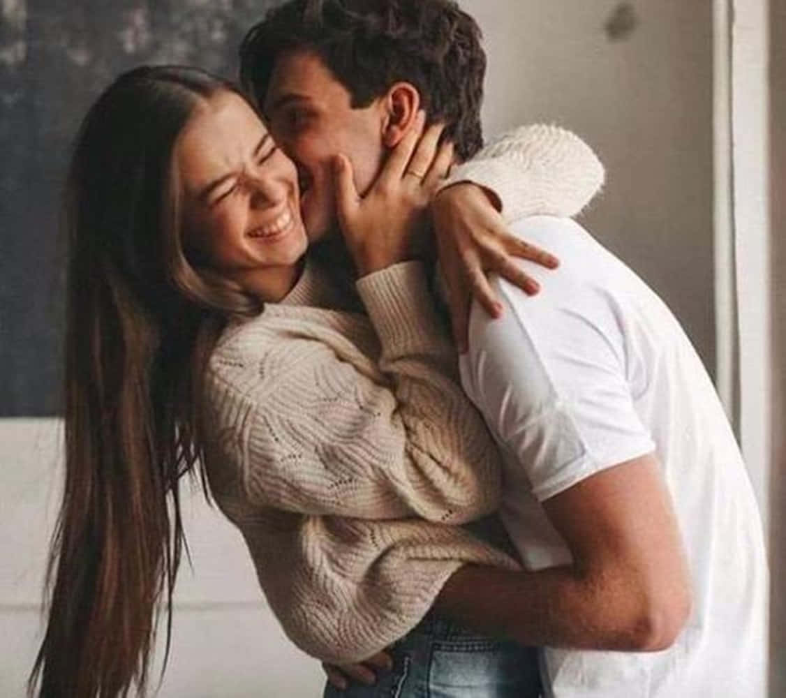 Girlfriend And Boyfriend 桌布 壁紙 — 一對快樂的情侶在室內溫暖地擁抱，柔和自然光突顯他們的親密時刻。