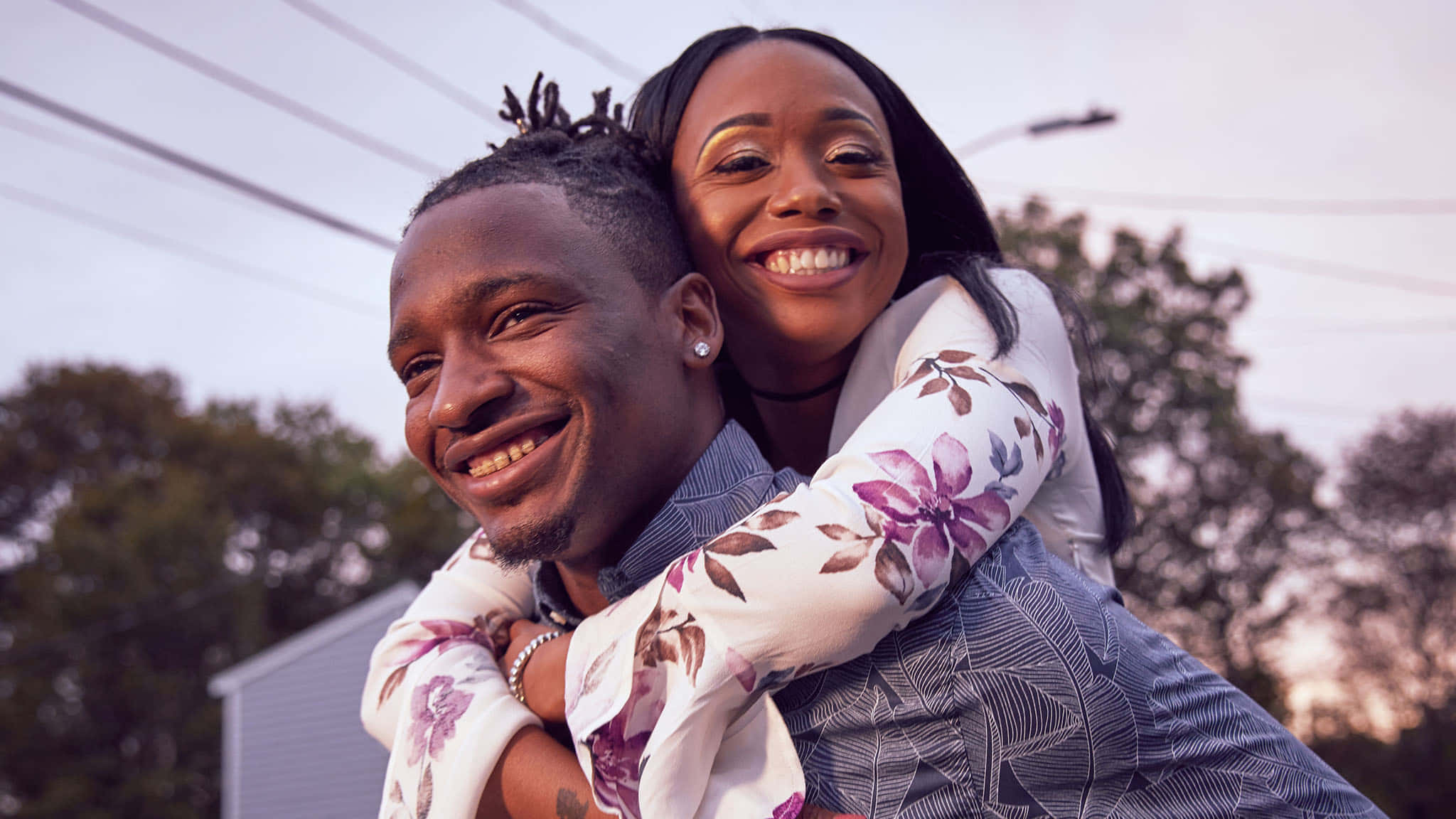 Black Couple 桌布 壁紙 — 一對快樂的情侶在戶外分享揹背，金色夕陽照耀著他們微笑的臉龐。