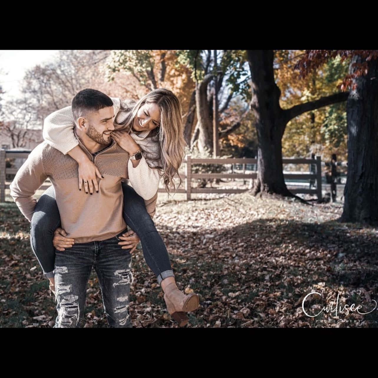 couple love 桌布 壁紙 — 一對快樂的情侶在金色秋樹下分享一個有趣的背負時刻，落葉鋪滿地面。