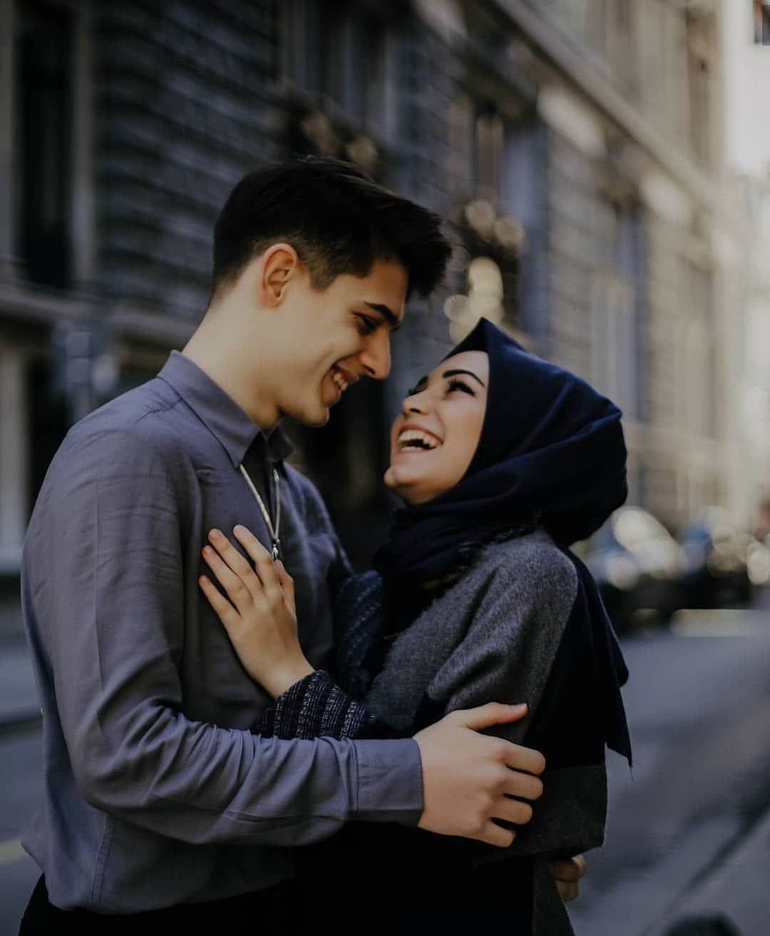 couple love 桌布 壁紙 — 一對快樂的情侶在陽光明媚的城市街道上擁抱大笑，身後是模糊的歷史建築。
