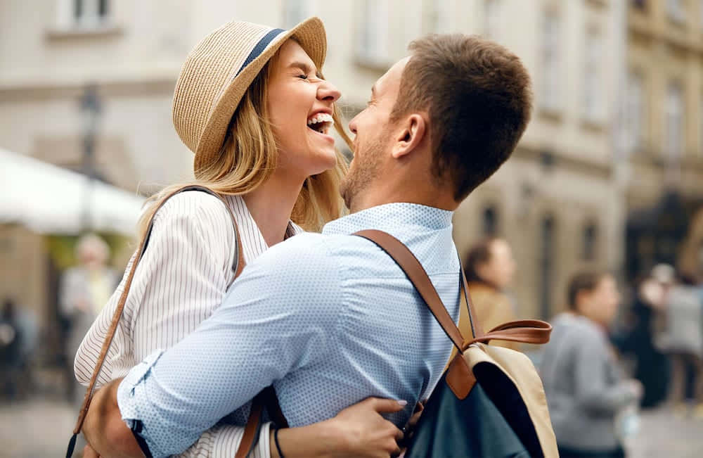 couple love 桌布 壁紙 — 一對快樂的情侶在陽光明媚的歐洲城市街道上擁抱並開懷大笑。