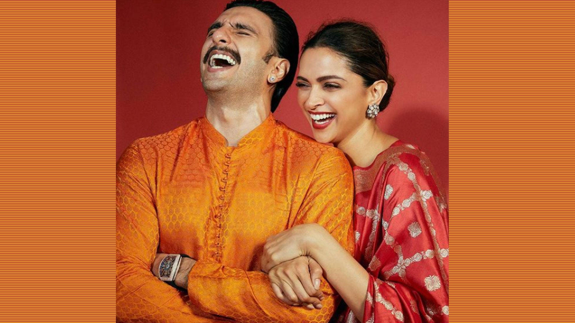 Ranveer Singh 桌布 壁紙 — 一對快樂的情侶穿著傳統印度服飾，在溫暖的紅橙色條紋背景前一起大笑。