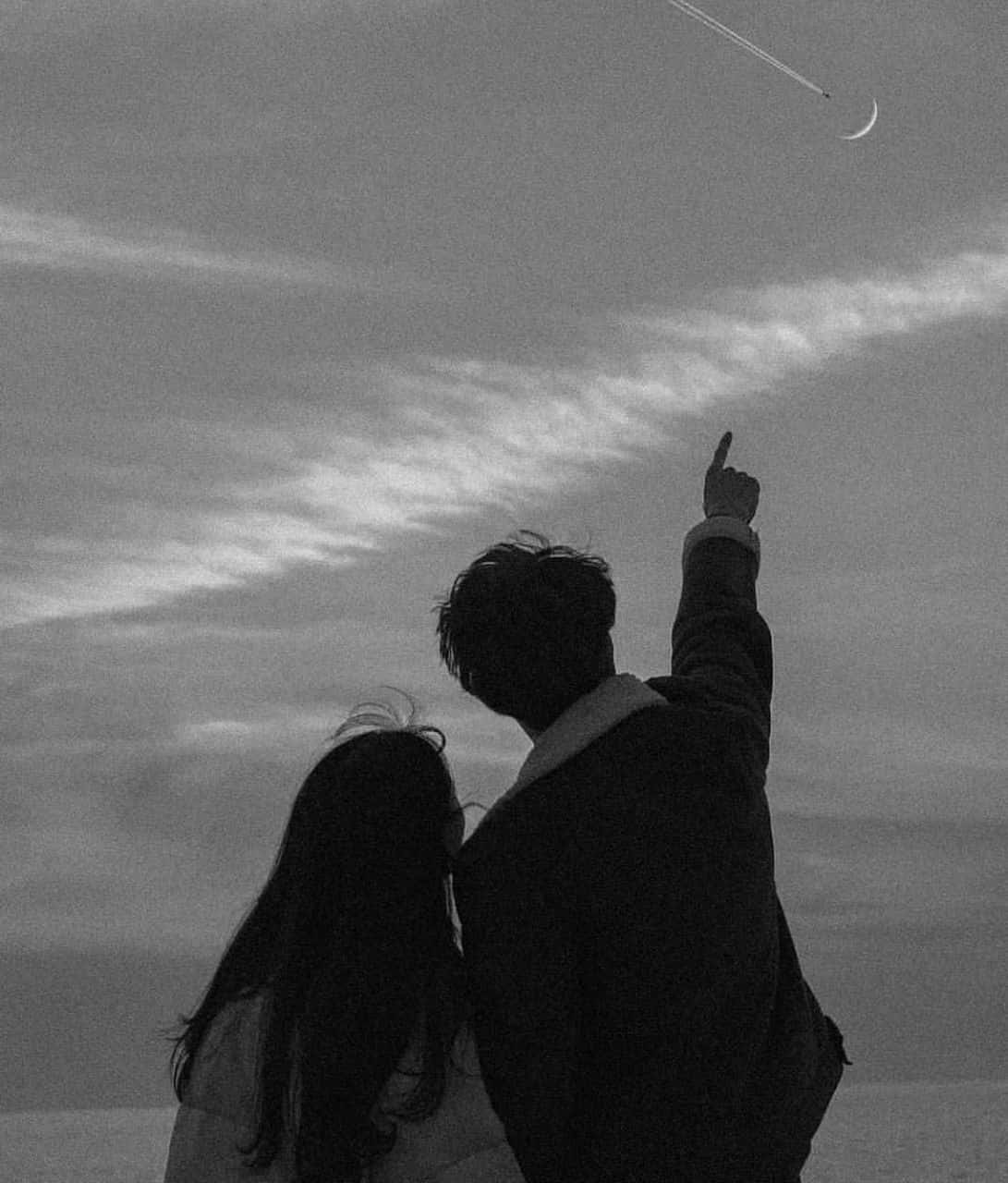 Falling In Love 桌布 壁紙 — 一對情侶以剪影仰望，一名男子指向被飛機雲劃過的彎月，背景是多雲的天空。
