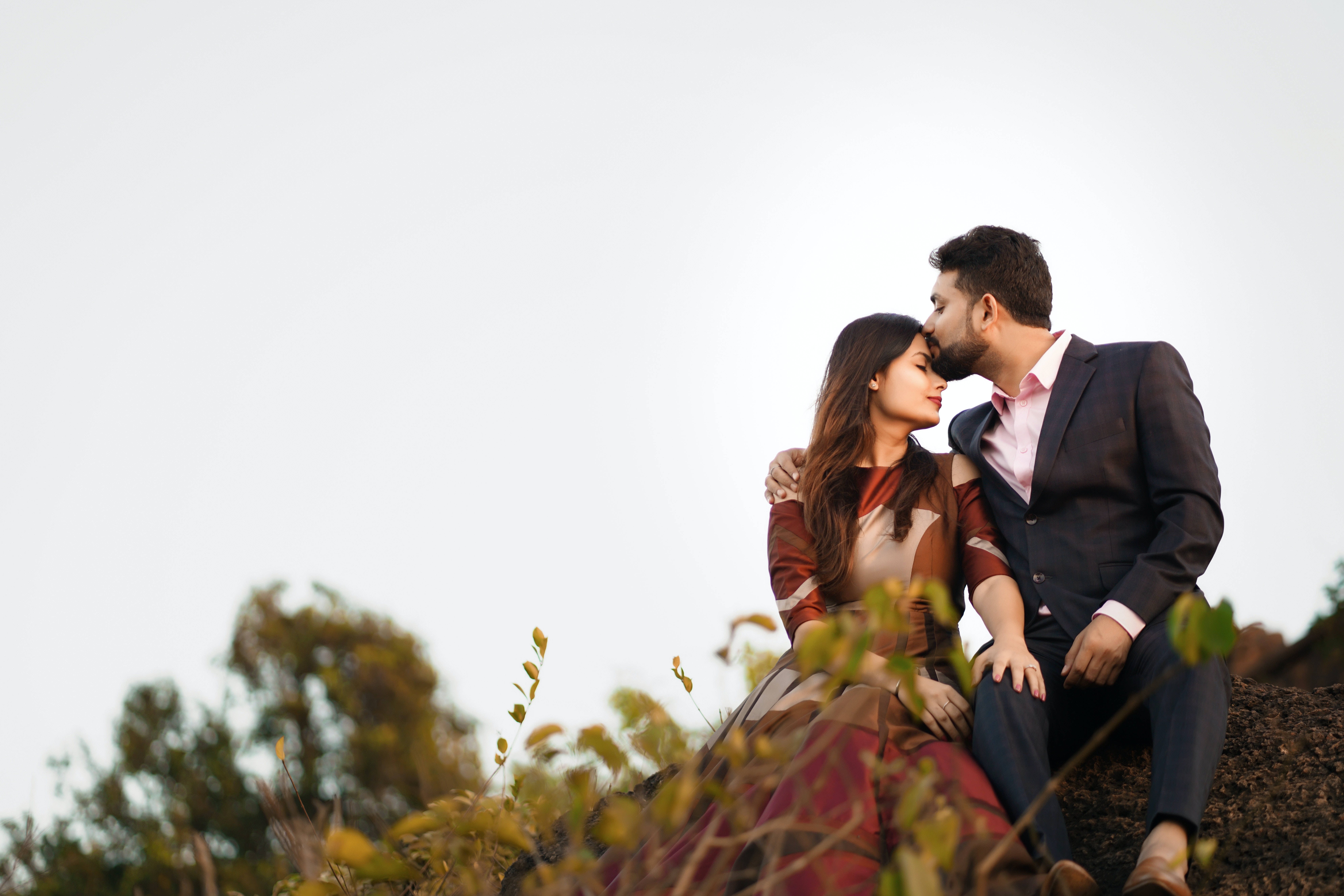 couple love 桌布 壁紙 — 一對情侶分享親密時刻，男人親吻女人的額頭，兩人坐在岩石山坡上。