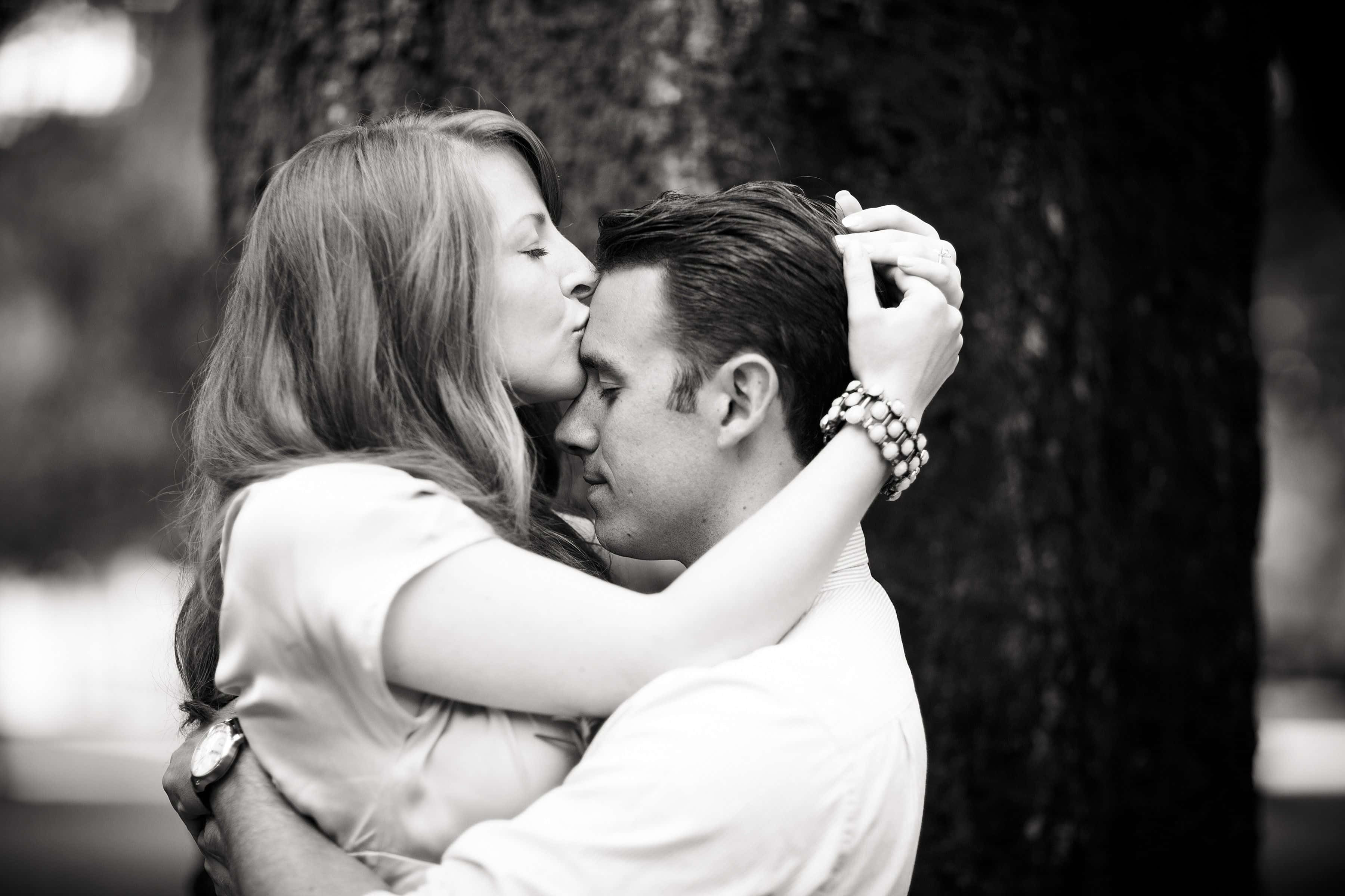 Forehead Kiss 桌布 壁紙 — 一對情侶在公園樹下擁抱親吻的黑白親密肖像。