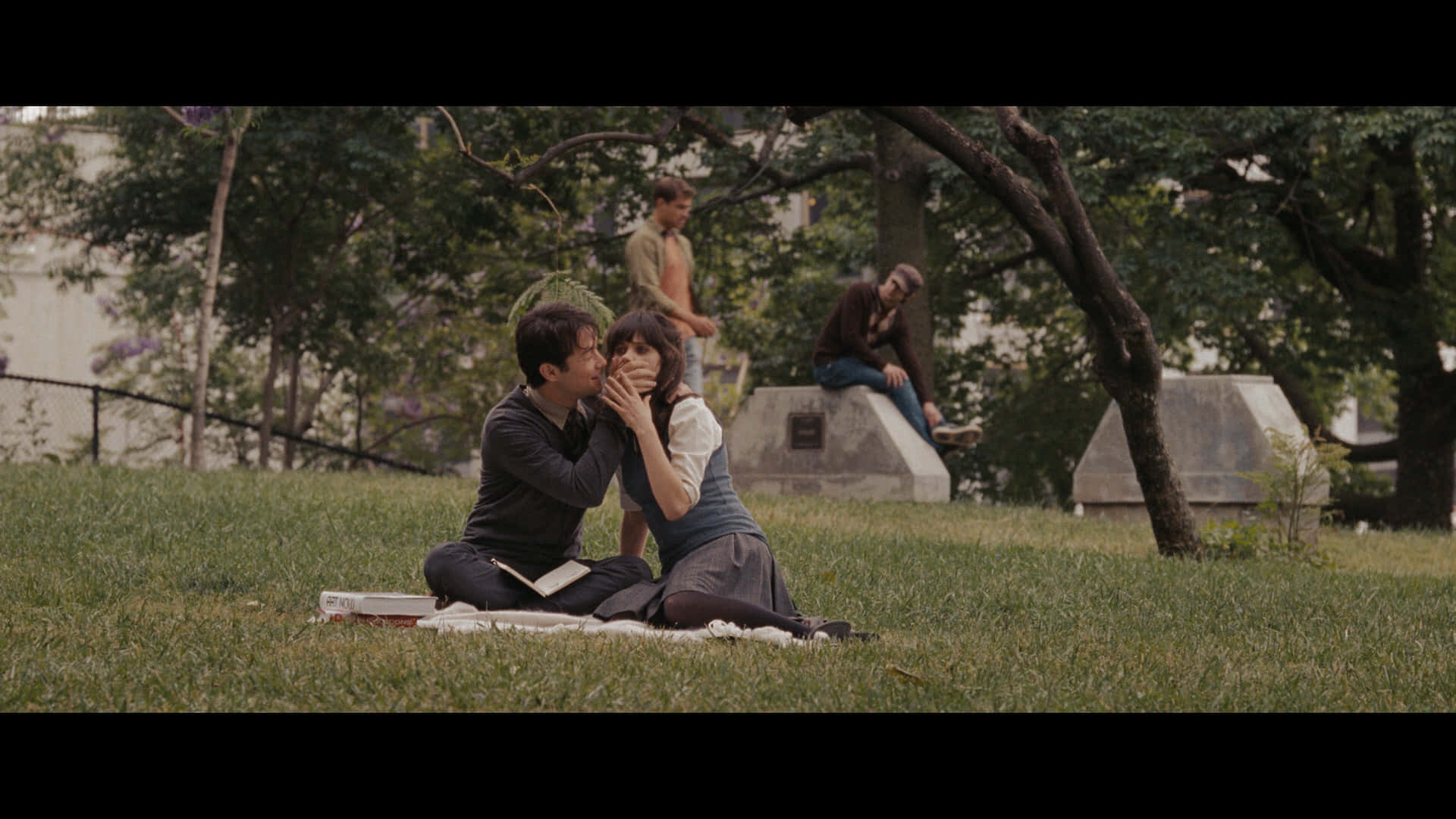 500 Days Of Summer 桌布 壁紙 — 一對情侶在公園草地上親吻，其他人則在附近的樹蔭下休息。