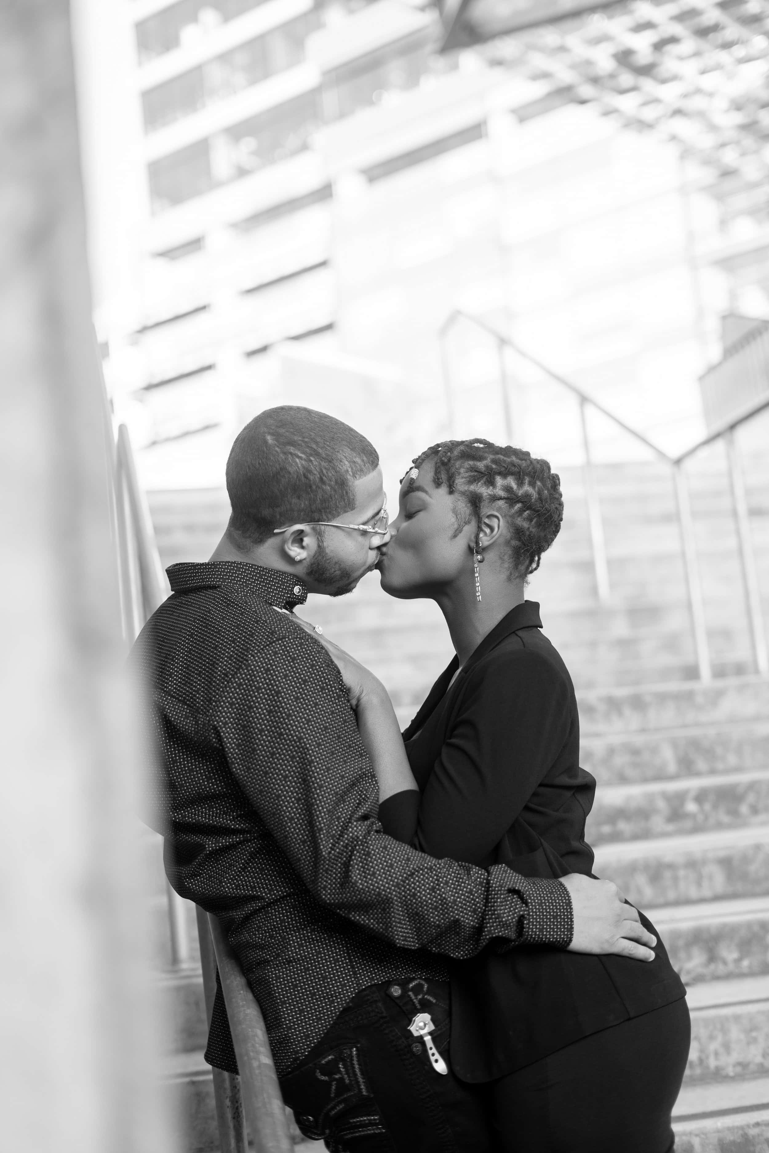 couples kissing 桌布 壁紙 — 一對情侶在城市樓梯上熱情接吻的黑白照片，背景是現代建築。
